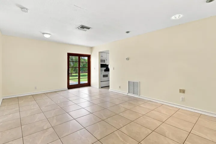 Spacious tiled living area with neutral finishes, recessed lighting, and access to the rear of the home.