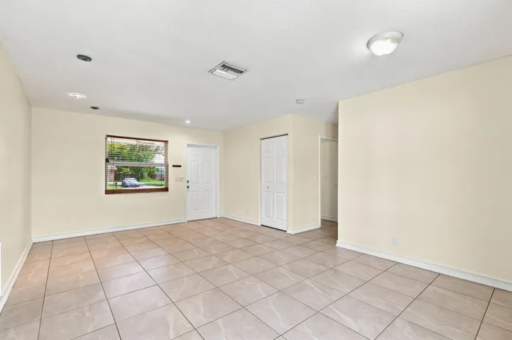 Spacious tiled interior with neutral walls and multiple windows for natural light.