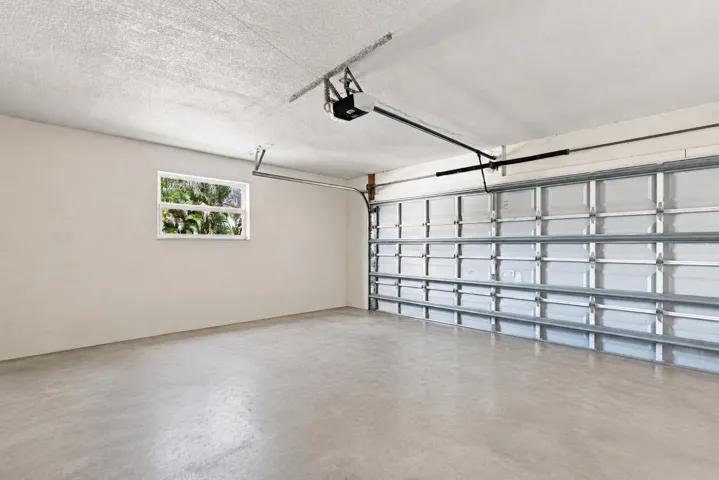 Attached garage with finished walls, overhead garage door, and additional storage space.