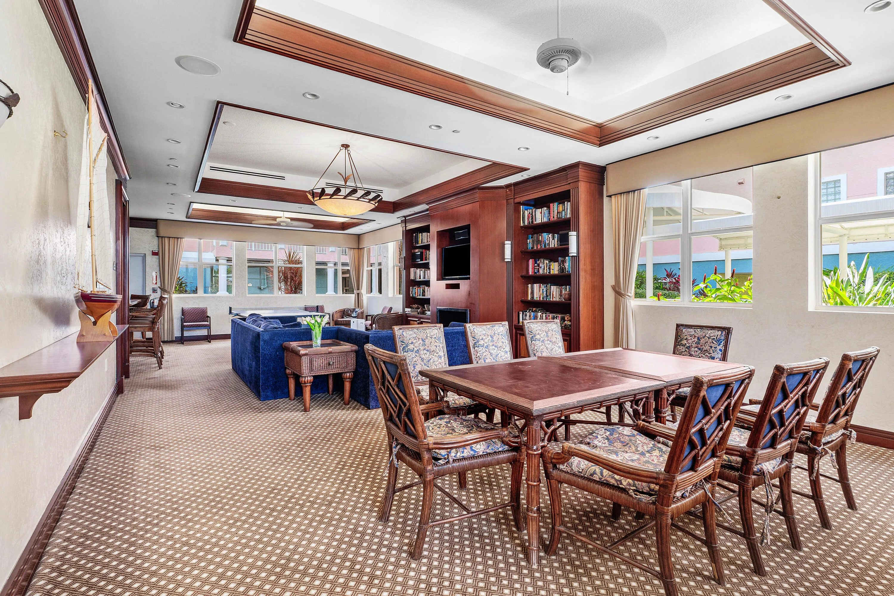 Spacious room featuring patterned carpet, recessed lighting, and a tray ceiling with wood-finish trim