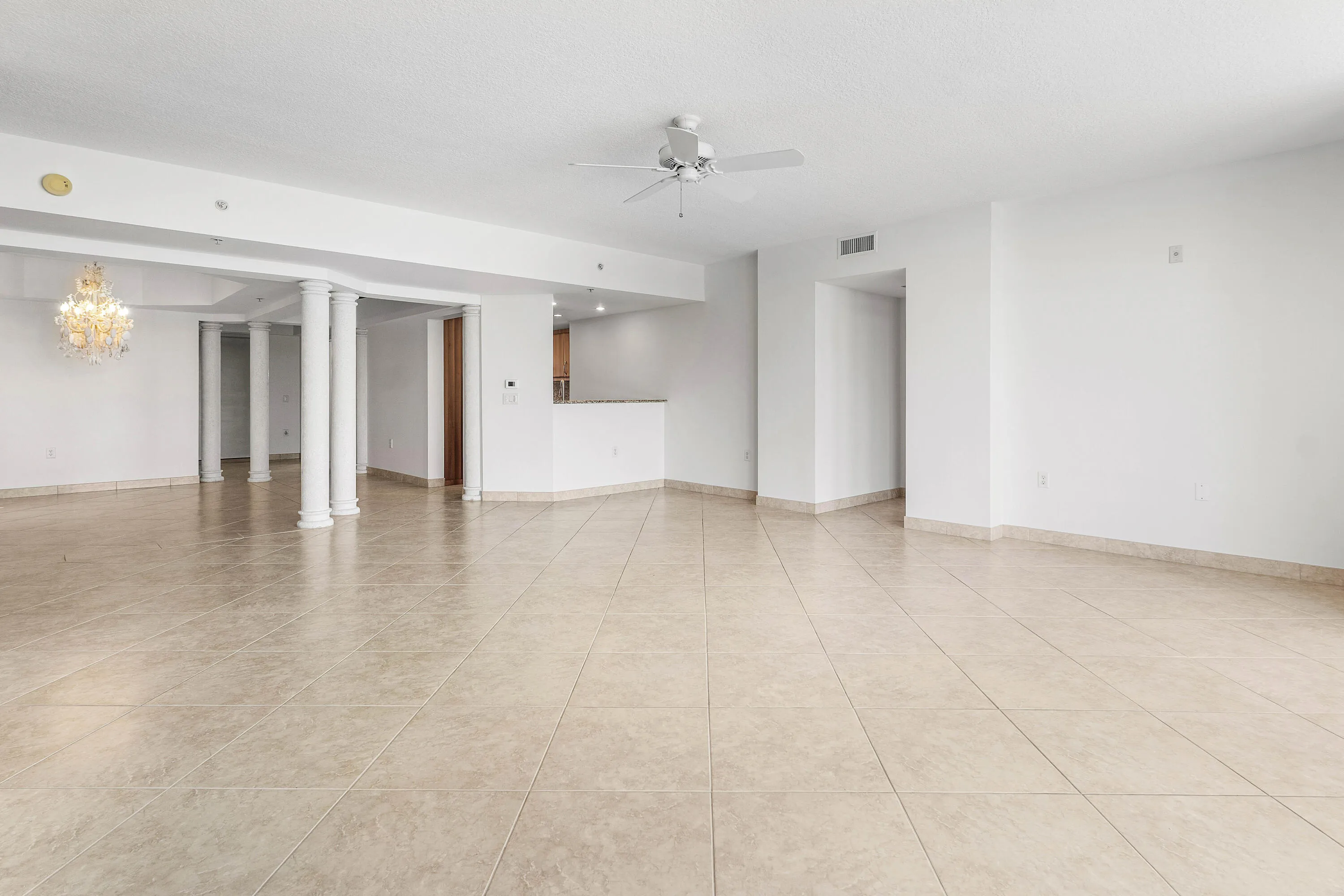 Neutral-toned tile flooring, white walls, ceiling fan, circular window, and sliding glass door to a balcony