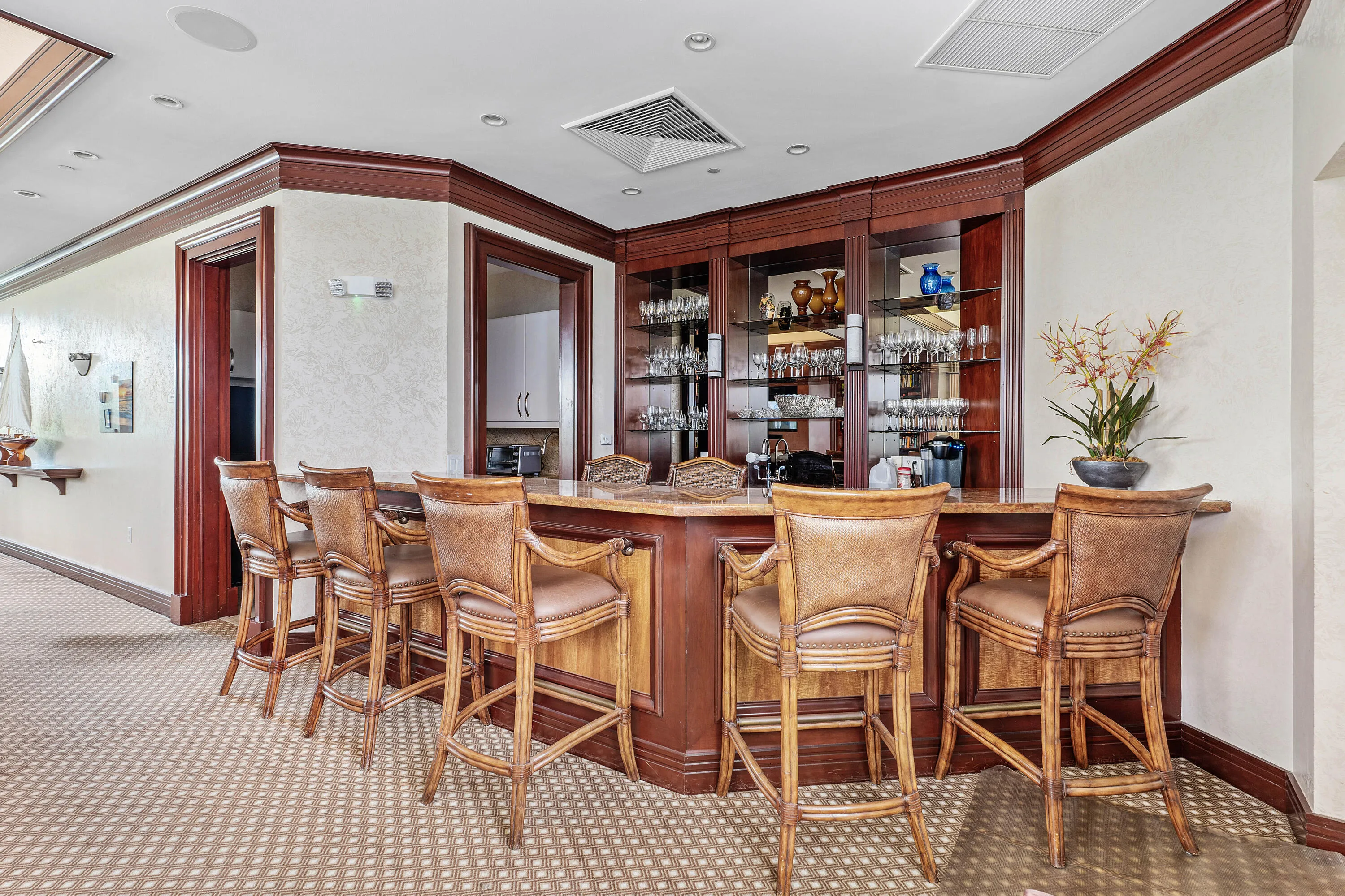 Built-in wet bar with wood cabinetry, glass display shelving, and a countertop