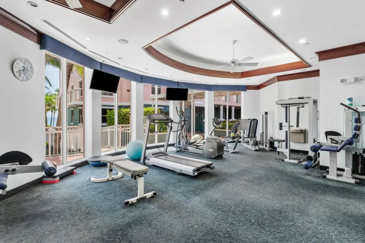 Fitness center with a coved ceiling, recessed lighting, and a ceiling fan