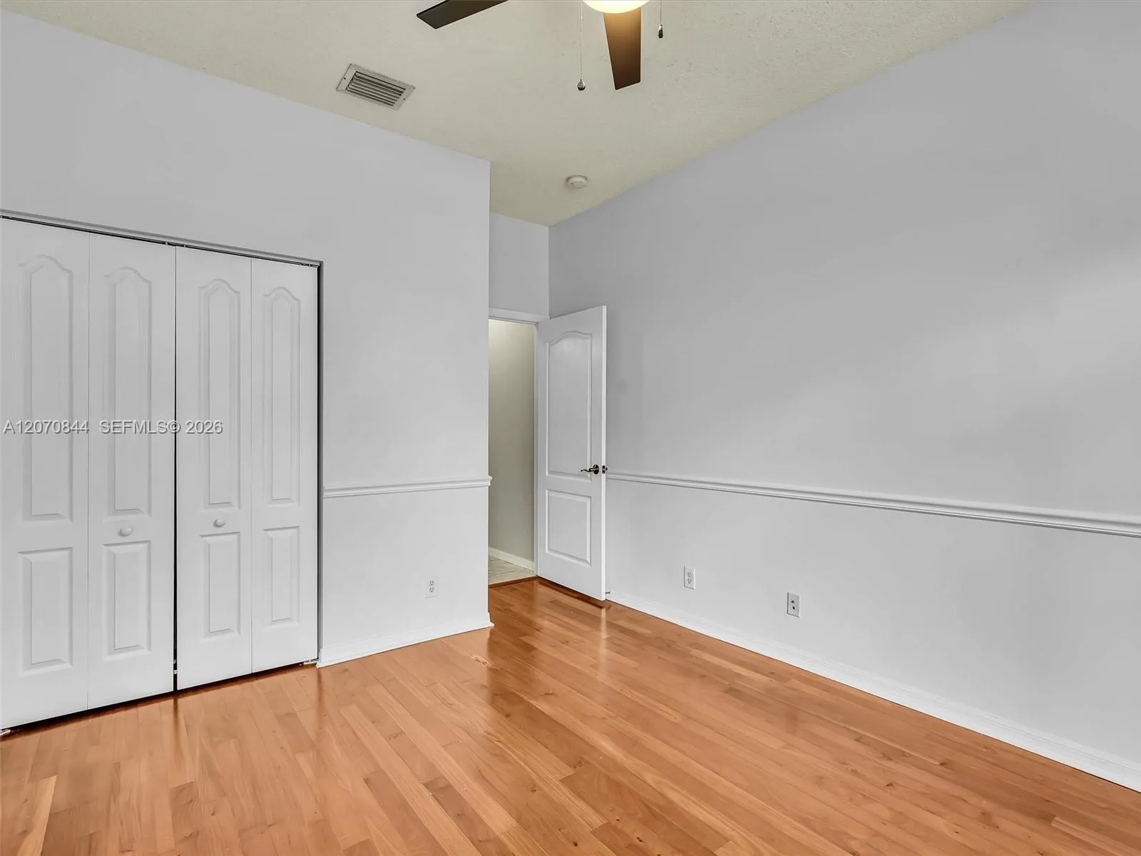 Spacious second bedroom featuring hardwood floors, a charming bay window, and abundant natural light, creating a warm and inviting space.