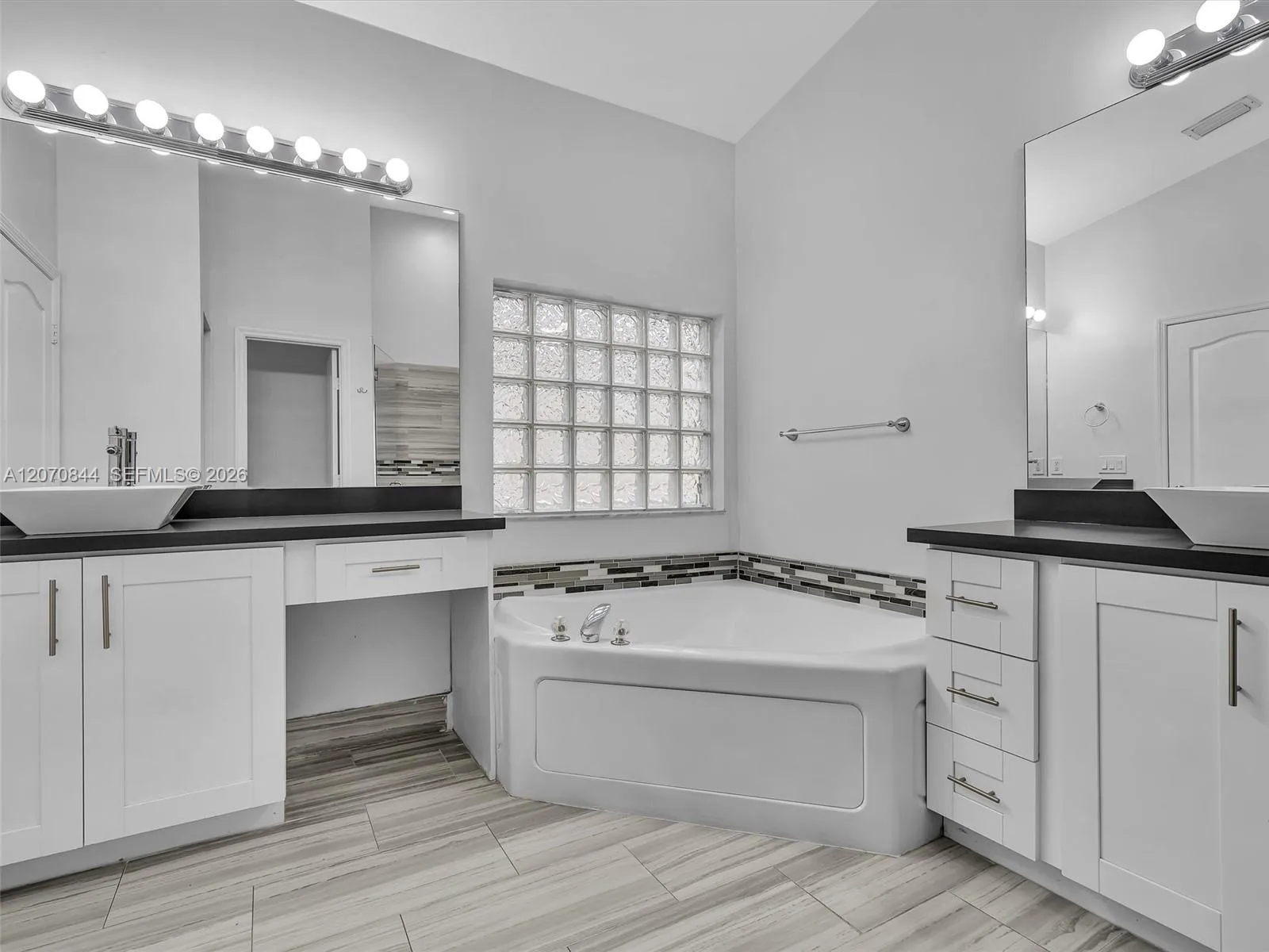 Spacious primary bathroom featuring dual vanities, a large soaking tub, a walk-in shower with glass doors, and a separate private toilet area for added privacy.