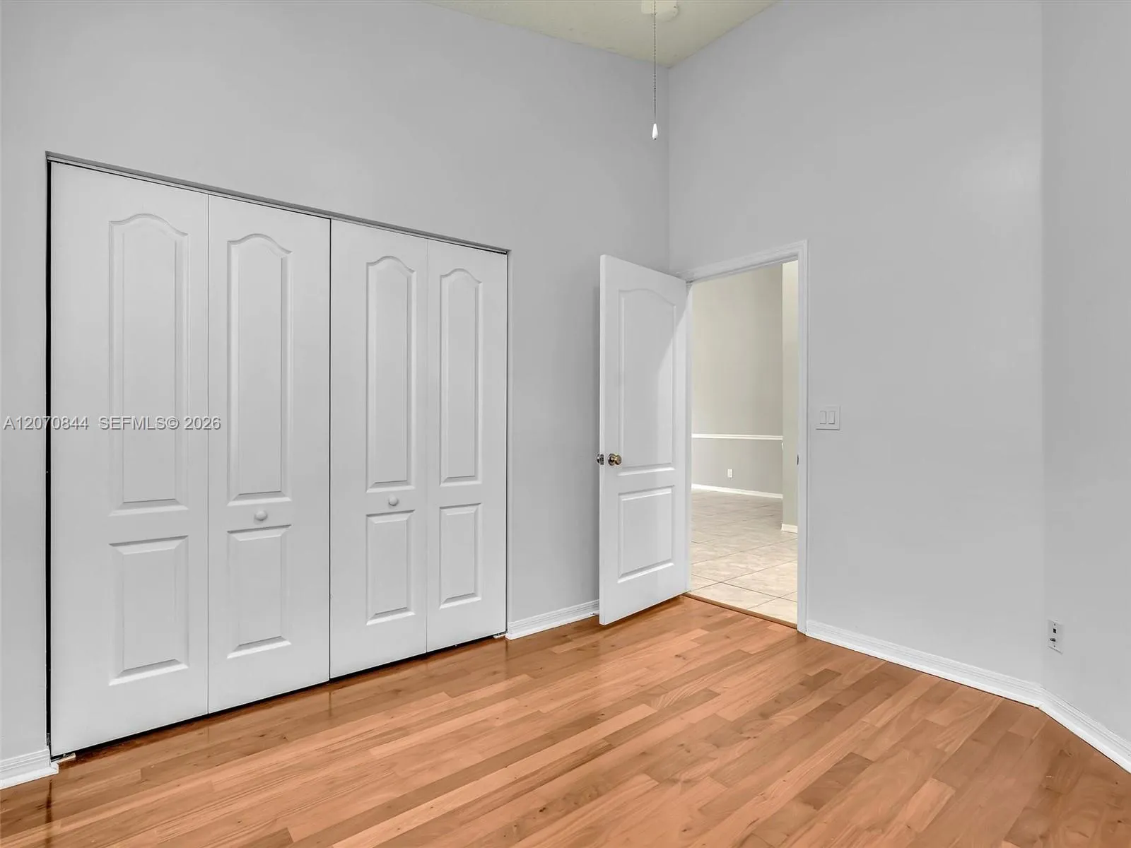 Comfortable third bedroom featuring hardwood floors and abundant natural light, offering a cozy yet functional space.