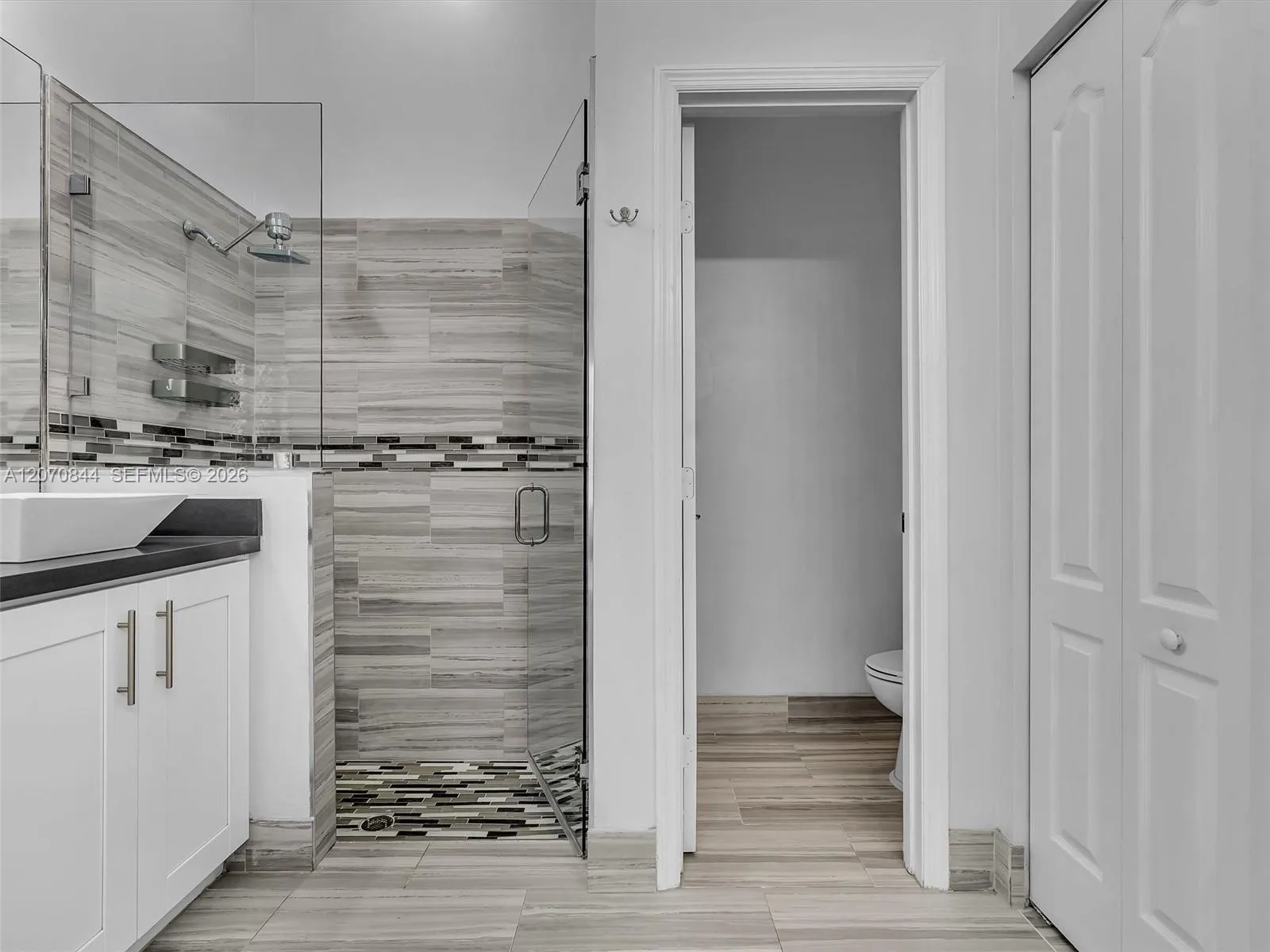 Spacious primary bathroom featuring dual vanities, a large soaking tub, a walk-in shower with glass doors, and a separate private toilet area for added privacy.