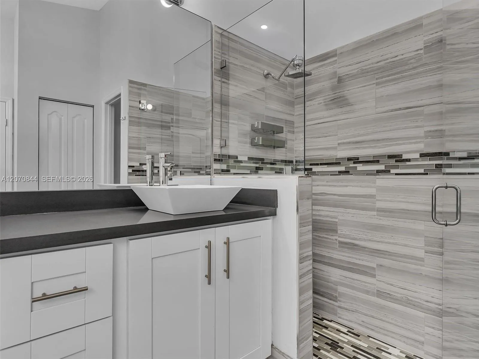 Spacious primary bathroom featuring dual vanities, a large soaking tub, a walk-in shower with glass doors, and a separate private toilet area for added privacy.