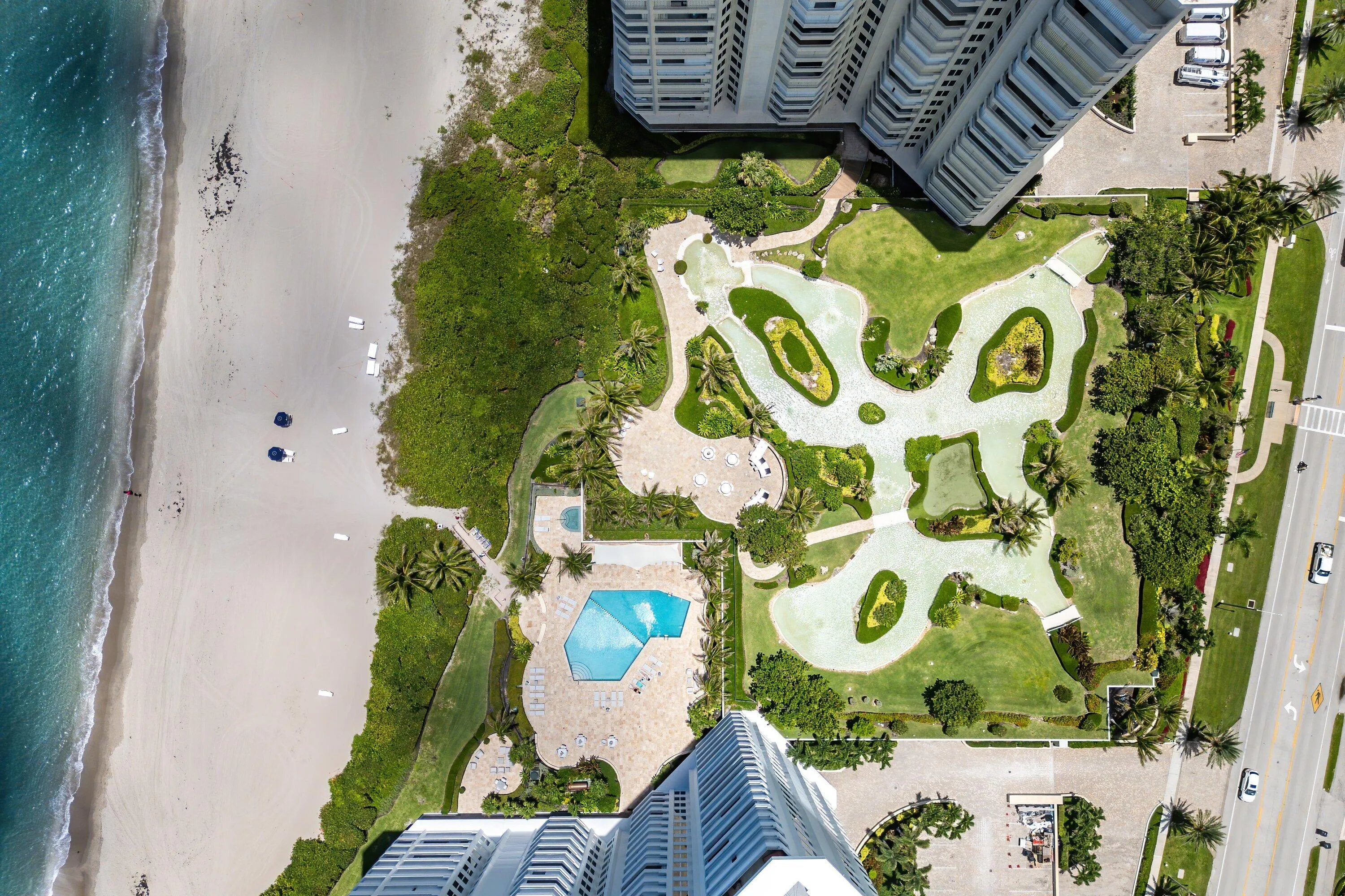 Beachfront property featuring multiple high-rise structures, extensive greenspace, a large aquatic amenity, and direct beach access