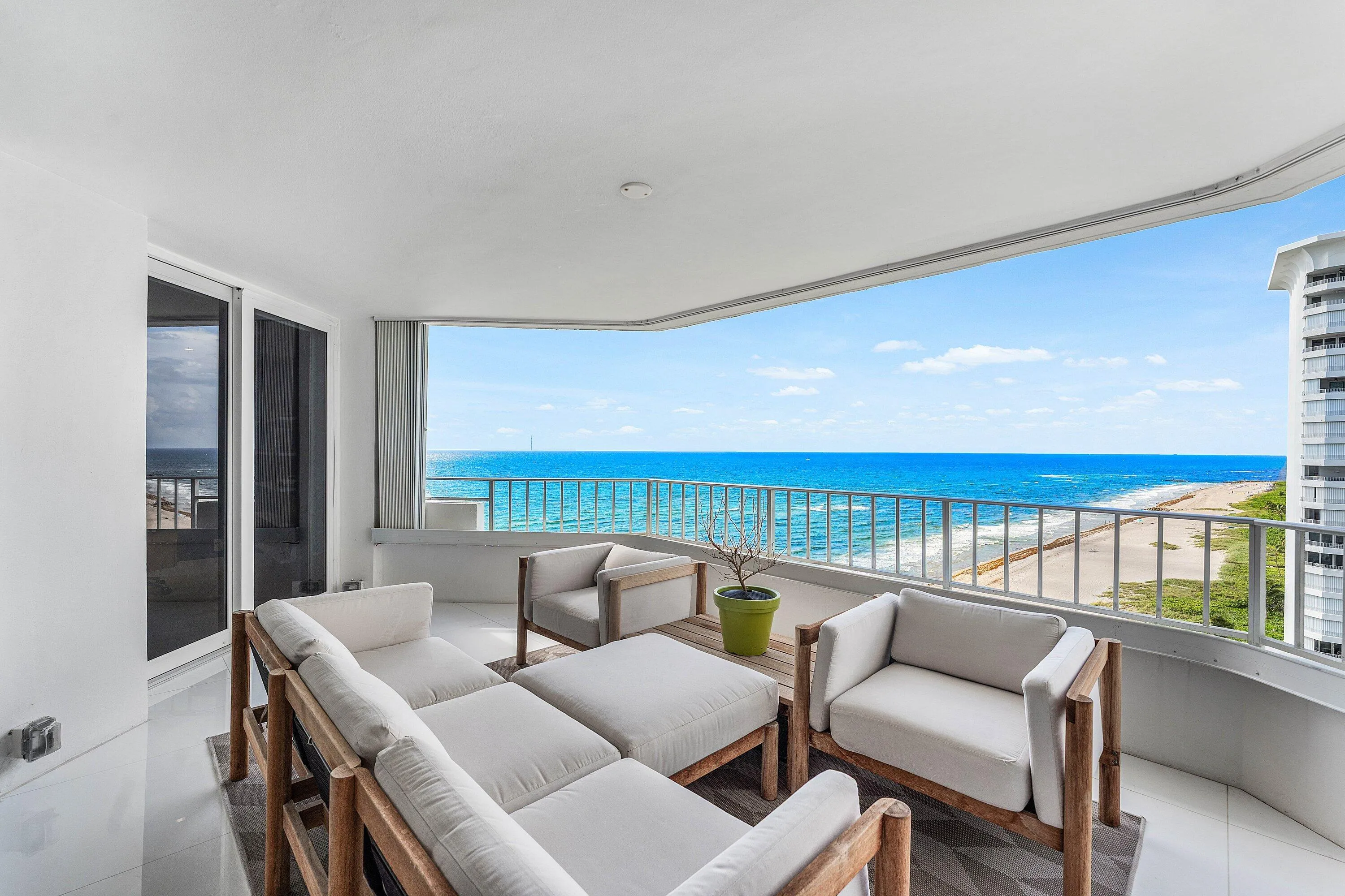 Expansive balcony with a curved ceiling, white railing, and sliding glass doors