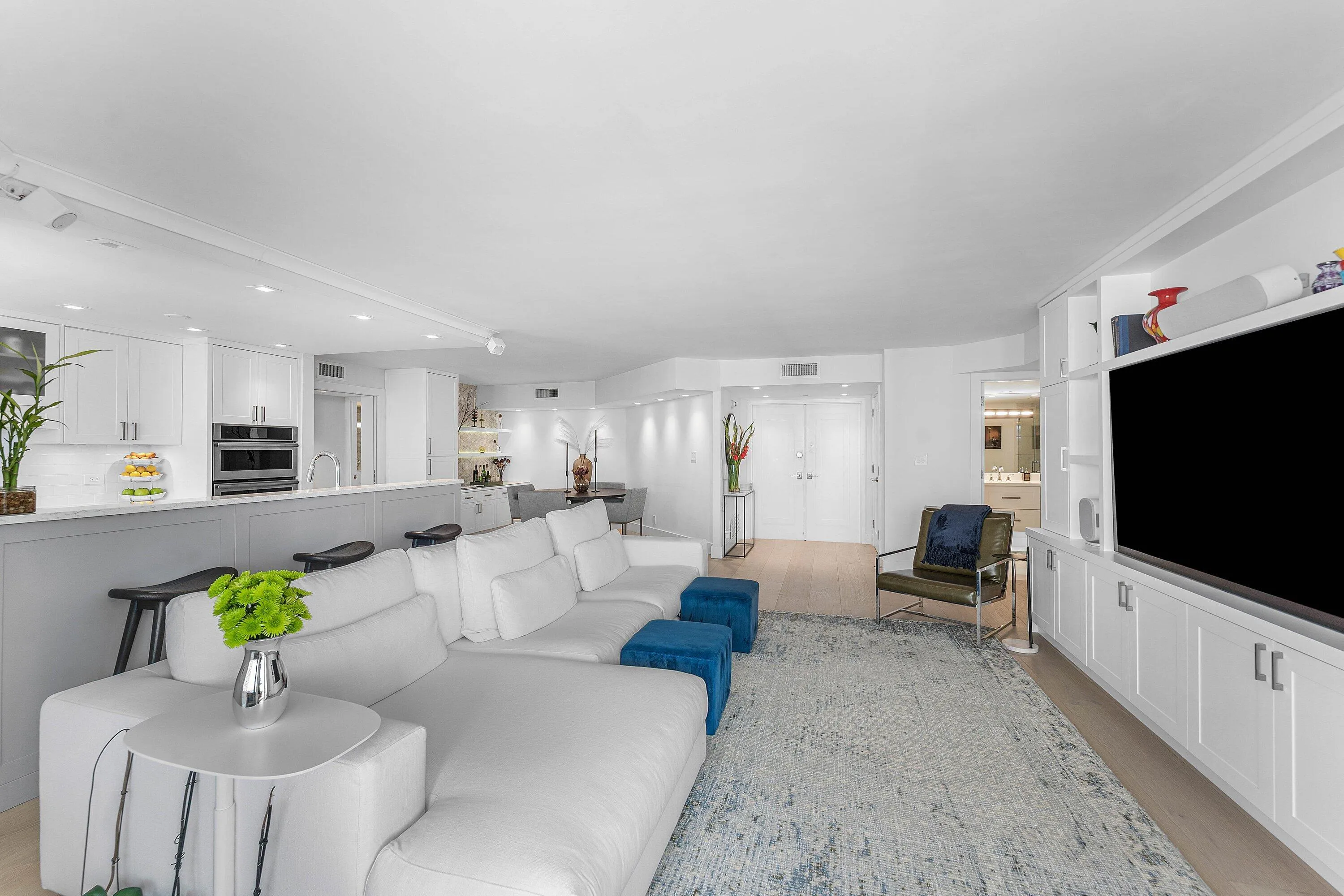 Open-concept living area with light wood-finish flooring, recessed lighting, and a built-in media center