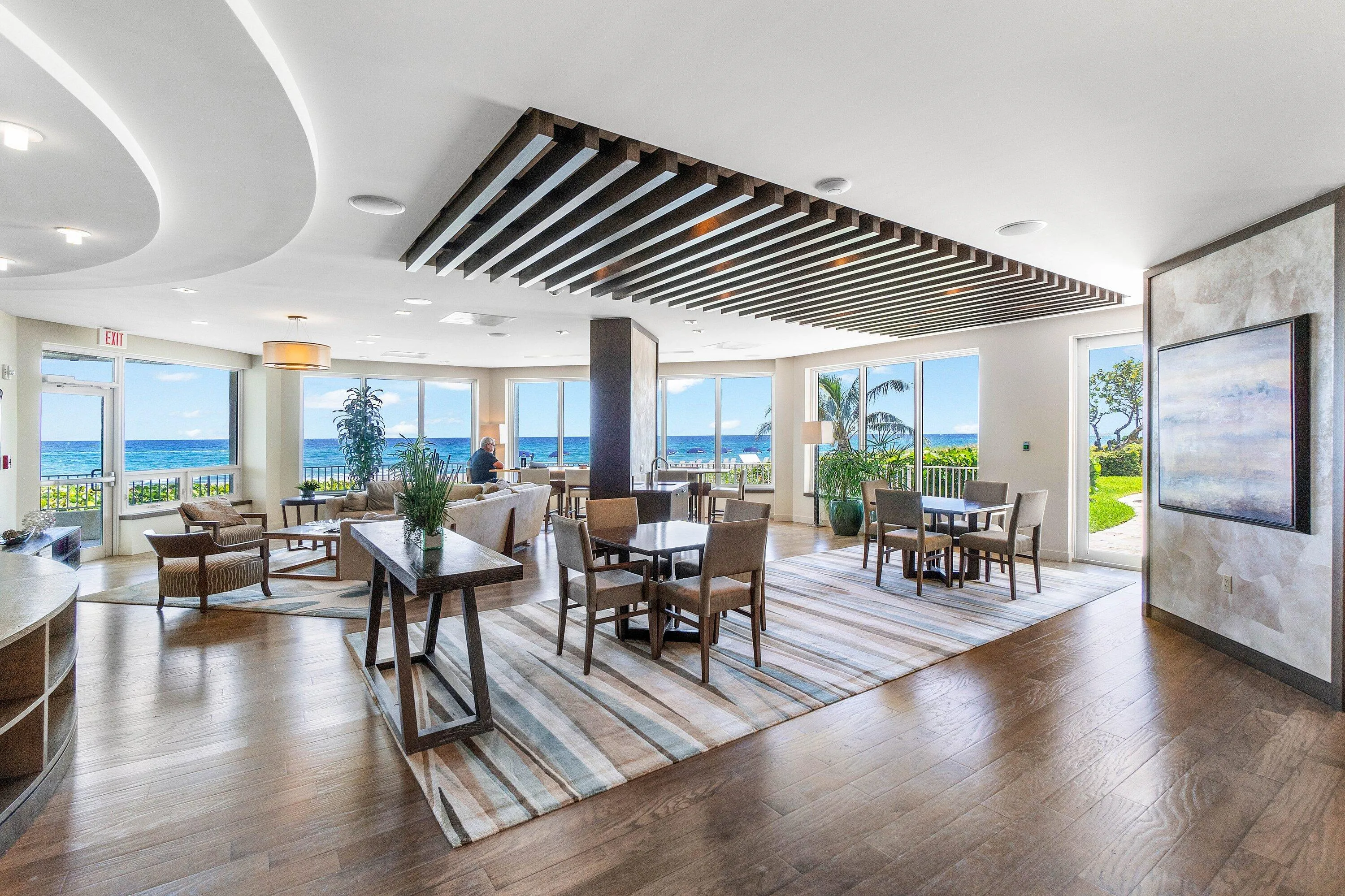 Expansive room featuring floor-to-ceiling windows, wood-finish flooring, and a decorative slatted ceiling accent