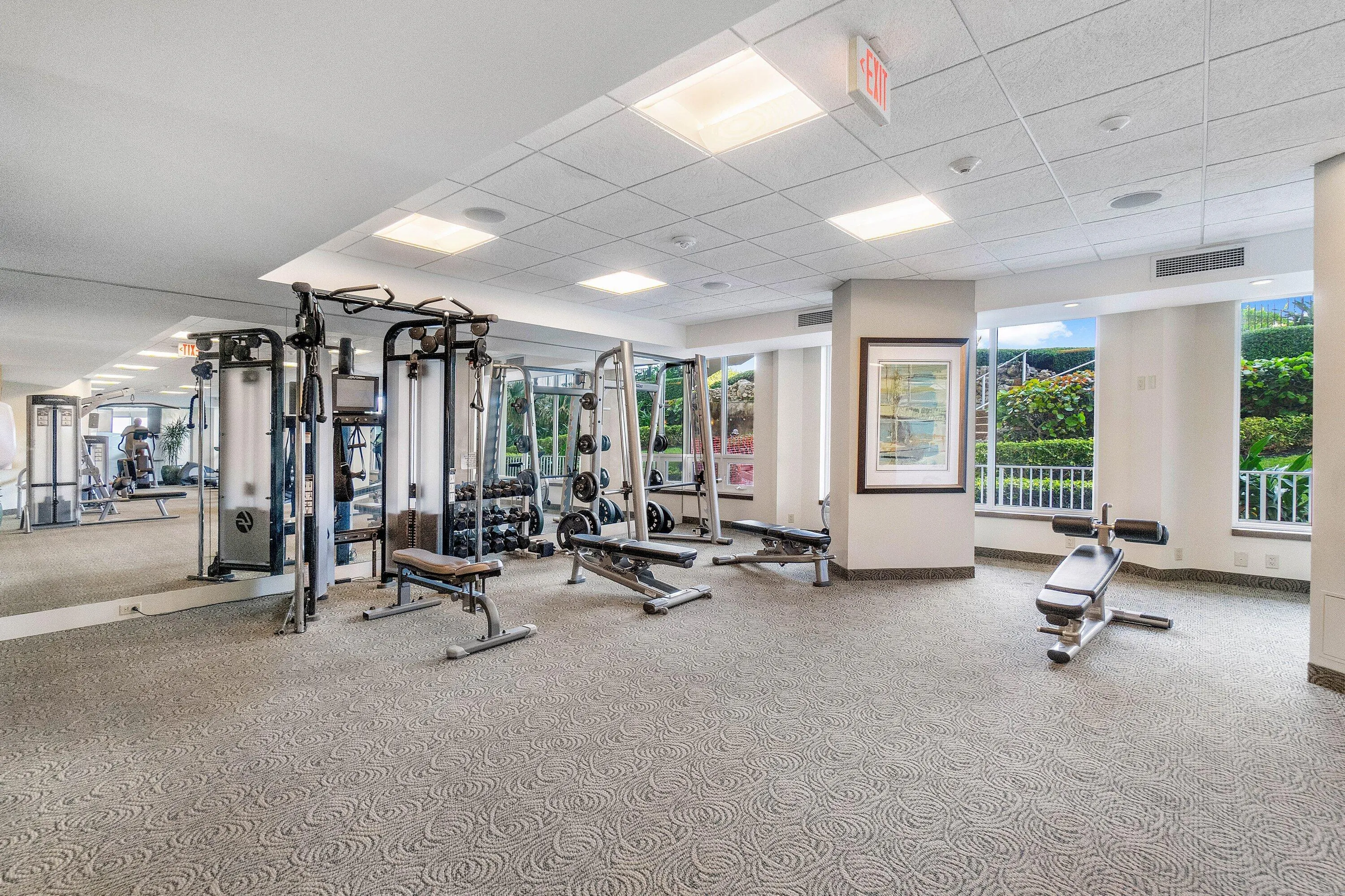 Fitness room featuring patterned carpet, recessed lighting, expansive mirrors, and large windows