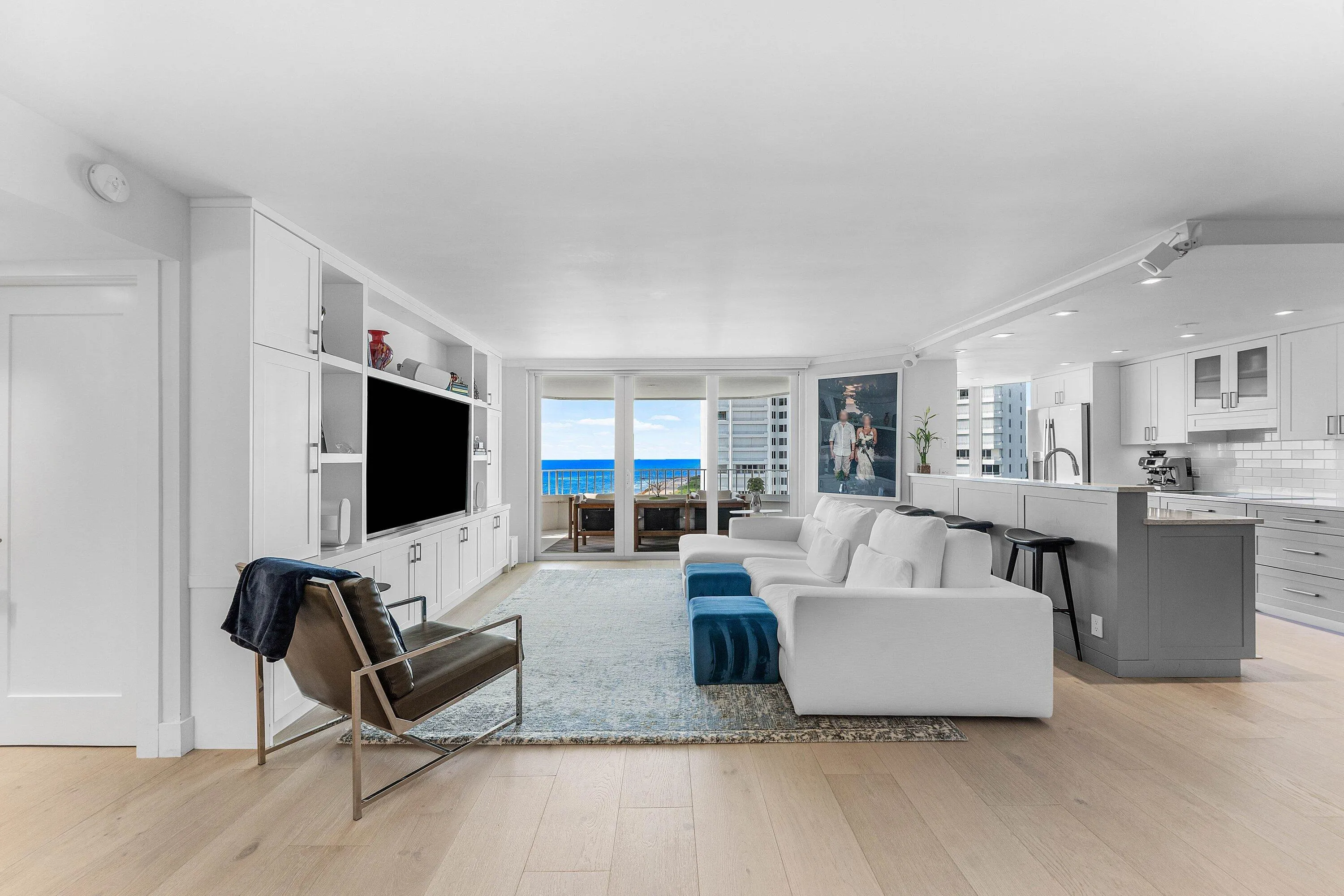 Open-concept living area with wood-finish flooring, built-in shelving, white cabinetry, and recessed lighting
