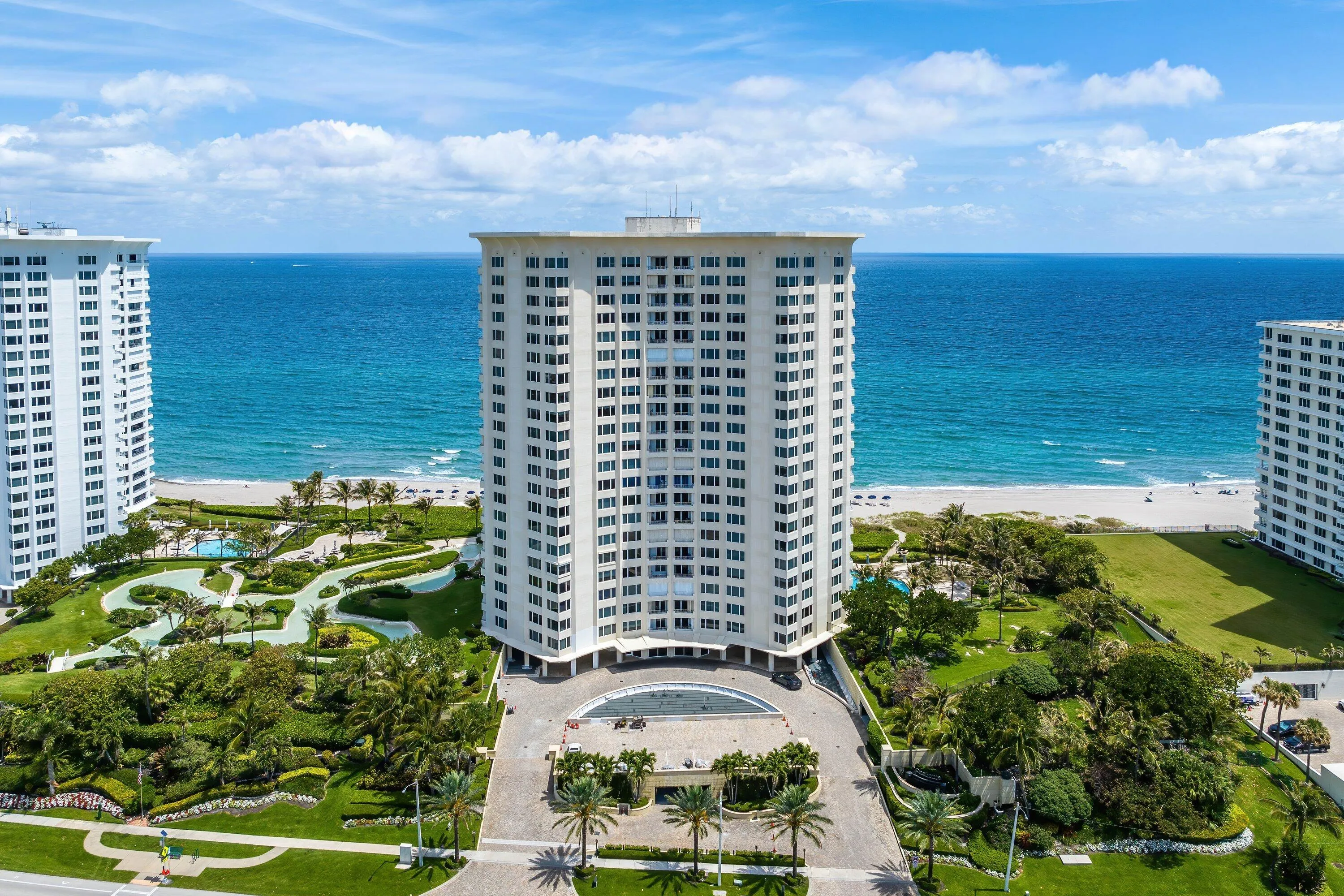 Oceanfront high-rise building with a circular driveway and lush landscaping