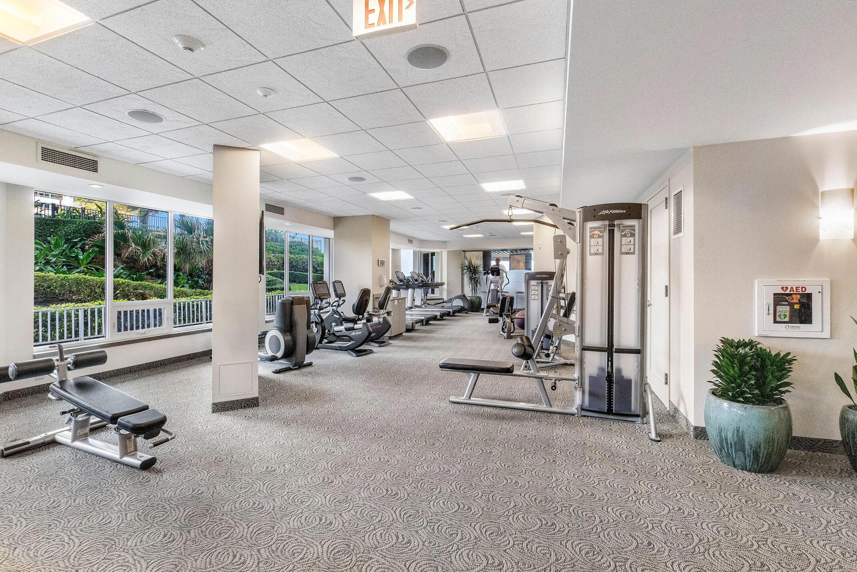 Fitness center with patterned carpet, expansive windows, and recessed lighting