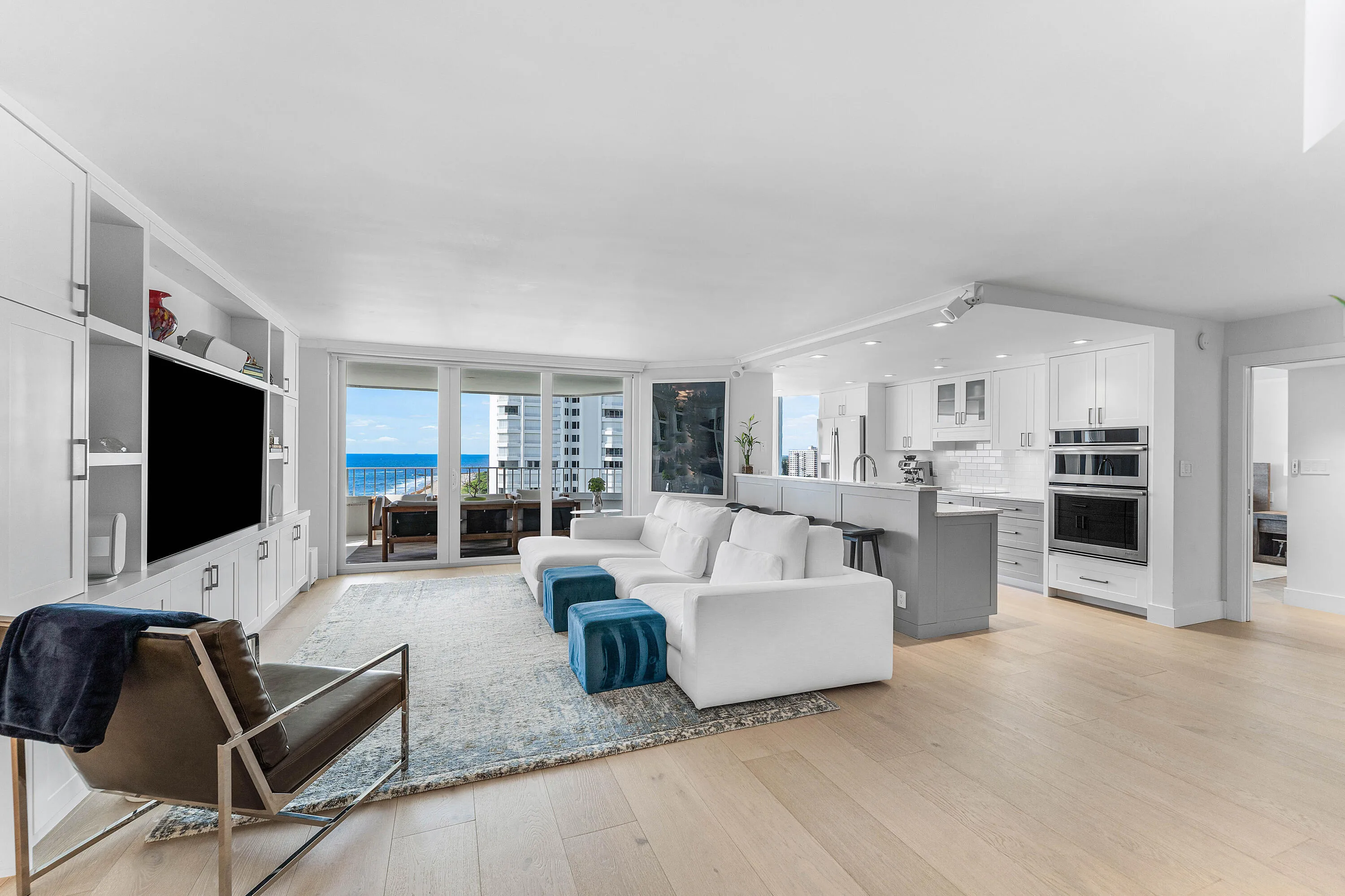 Open-concept living area with wood-finish flooring, built-in cabinetry, and a kitchen featuring a peninsula with seating