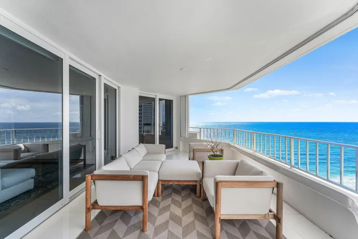 Expansive balcony with a white railing, large sliding glass doors, a white ceiling, and ocean scenery