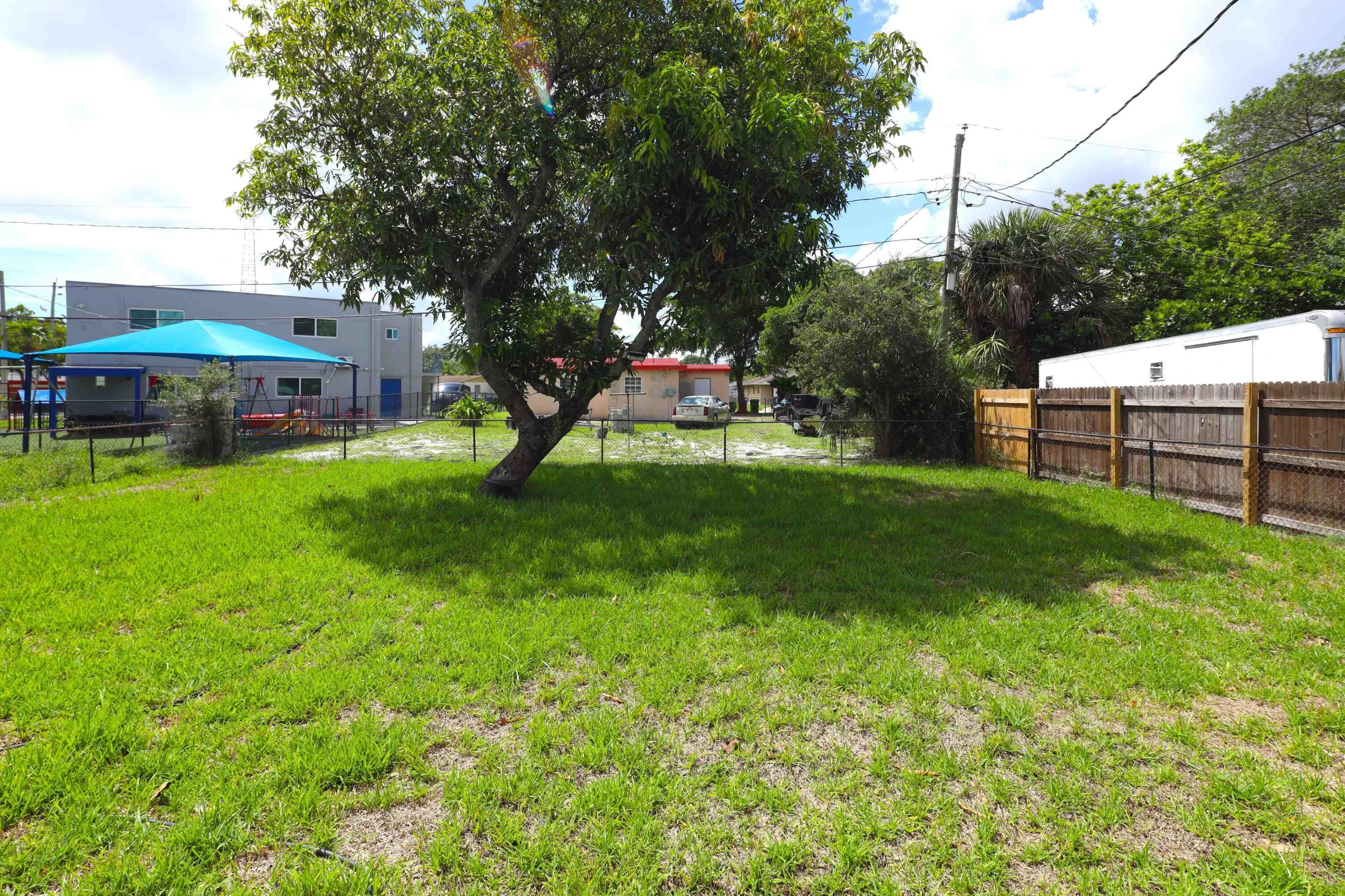 Spacious fenced backyard featuring a mature avocado tree with plenty of green space for pets, entertaining, gardening or creating your own South Florida backyard retreat.
