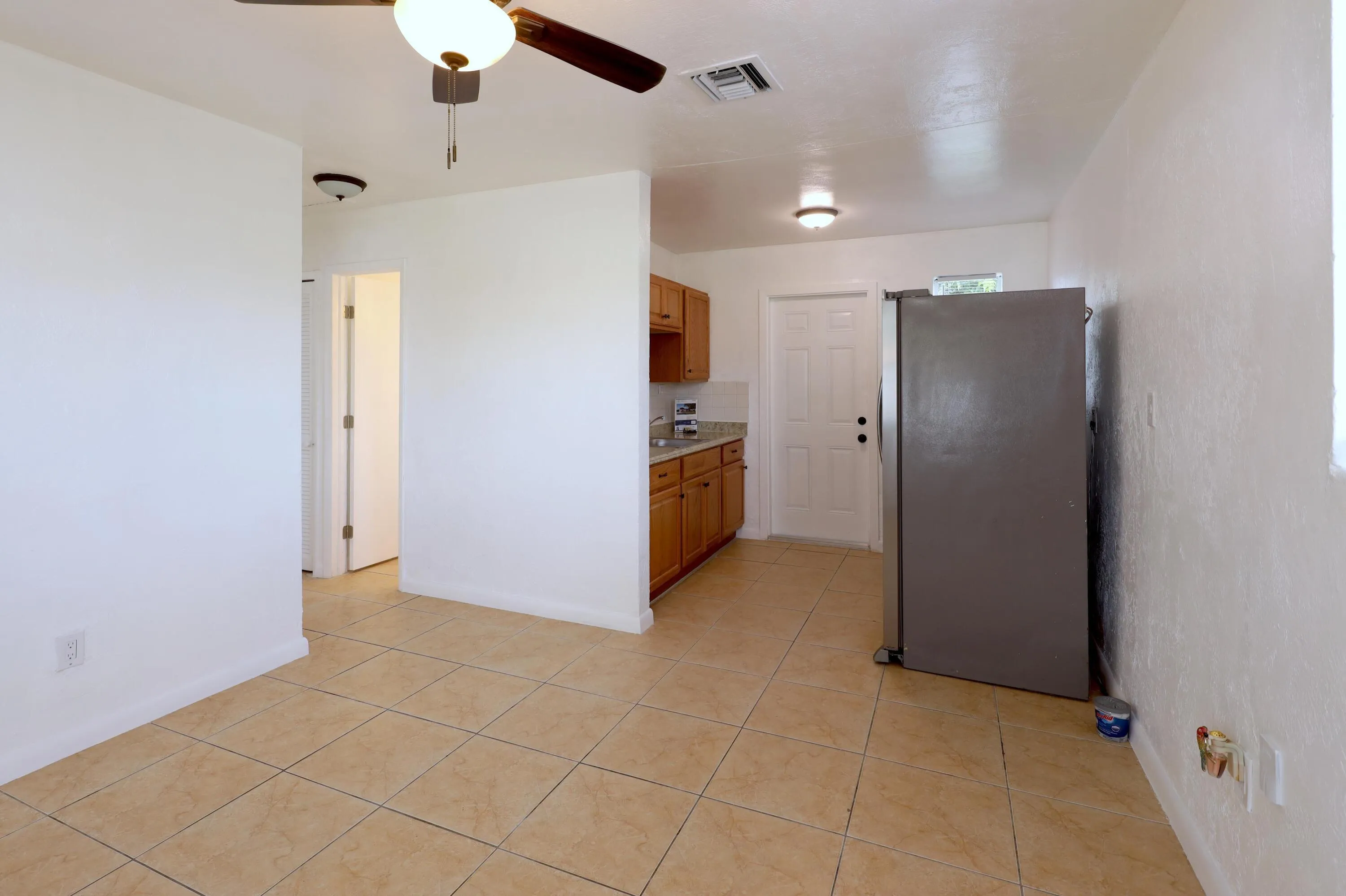 View from the living room toward the kitchen shows the home's comfortable layout, tile flooring and natural light. Affordable Fort Lauderdale home with no HOA.