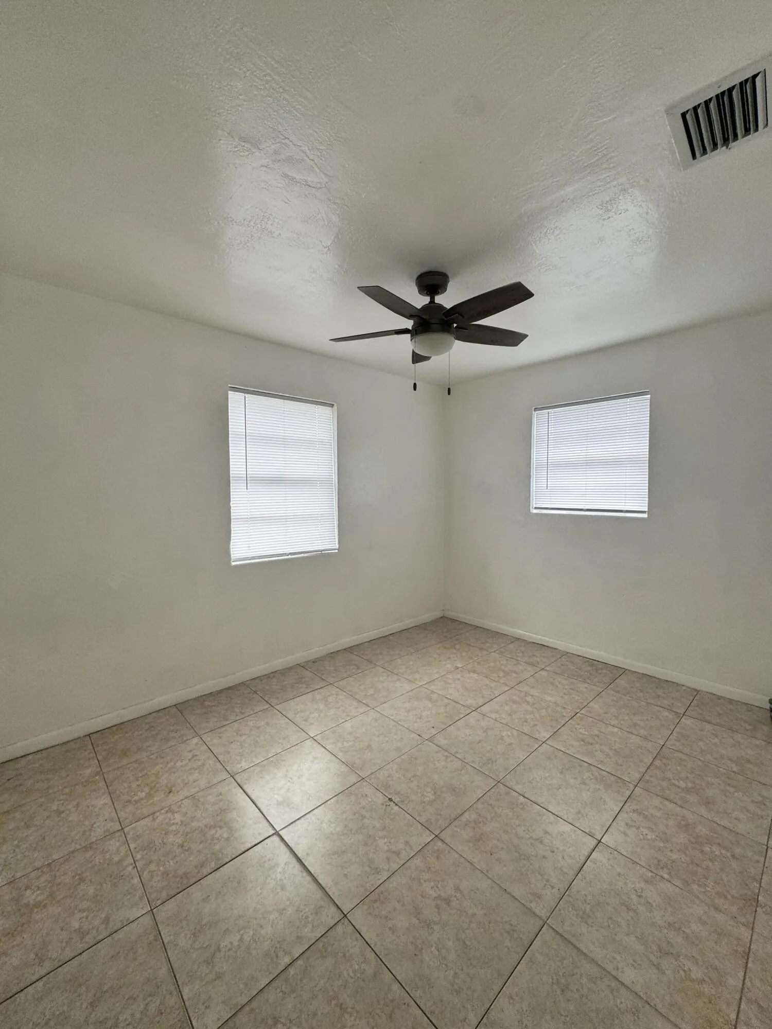 Bright bedroom with tile flooring, ceiling fan and natural light. Move in and add your own colors and personal touches to make this affordable Fort Lauderdale home your own. New Blinds
