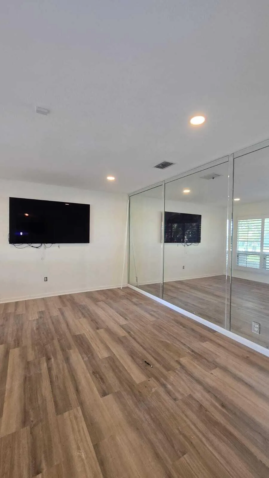 Wood-finish flooring, recessed lighting, and mirrored closet doors