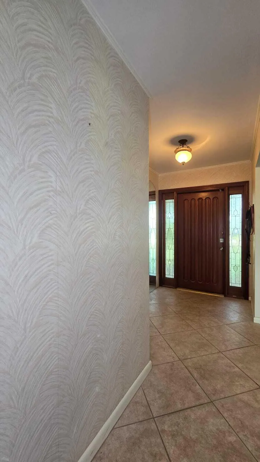 Paneled entry door with decorative glass sidelights, textured wall finish, tile flooring, and a flush-mount ceiling light fixture