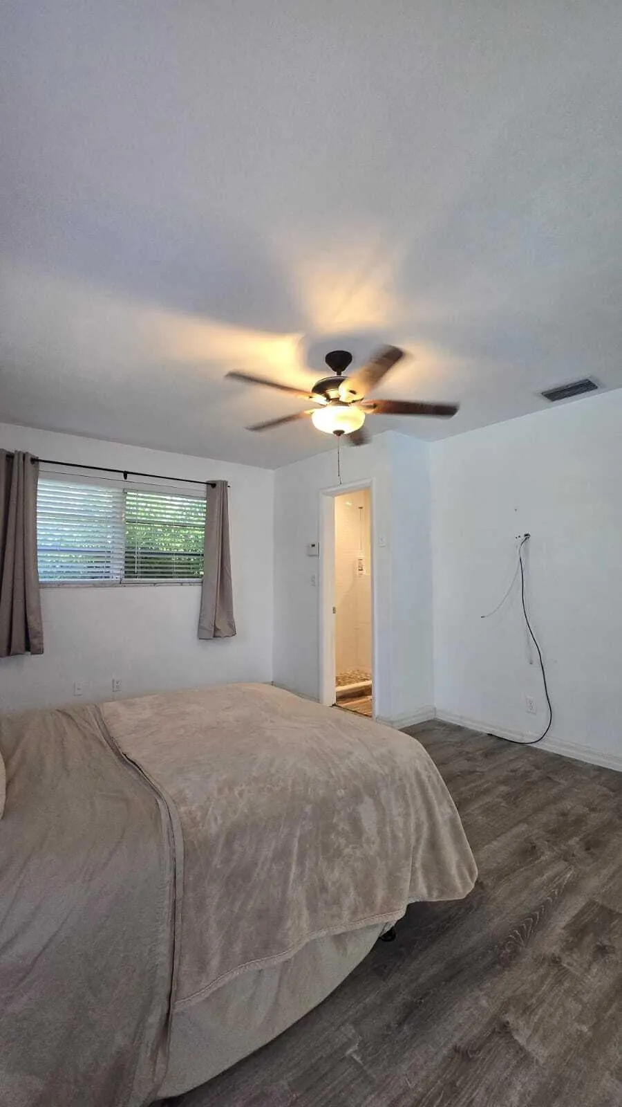 Wood-finish flooring, ceiling fan with integrated lighting, and window with blinds