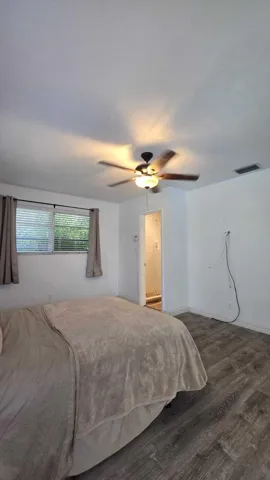 Wood-finish flooring, ceiling fan with integrated lighting, and window with blinds