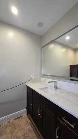 Dark wood-finish vanity with ample storage, integrated rectangular sink, and chrome-finish faucet