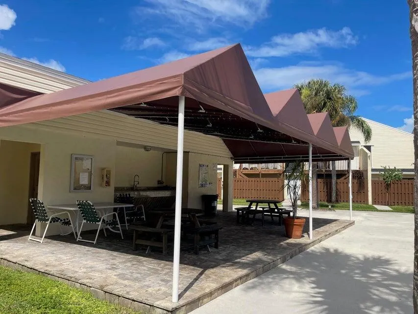 A SHADED PICNIC AREA WITH TABLES & CHAIRS, SINK AND RESTROOMS.