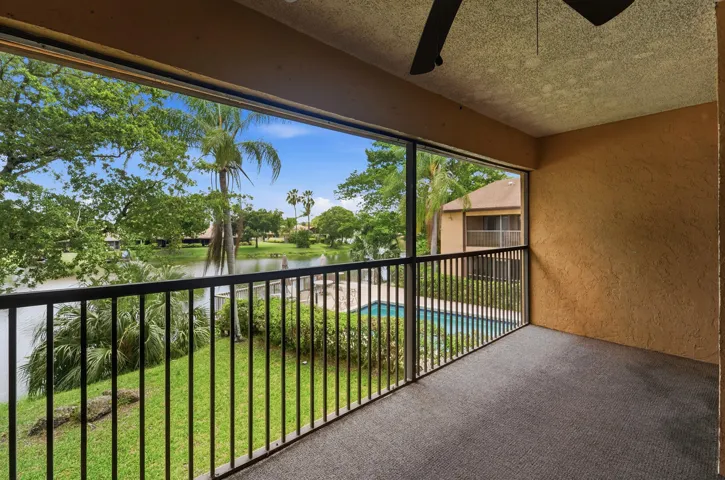 Screened patio with a ceiling fan, carpeted flooring, and textured walls