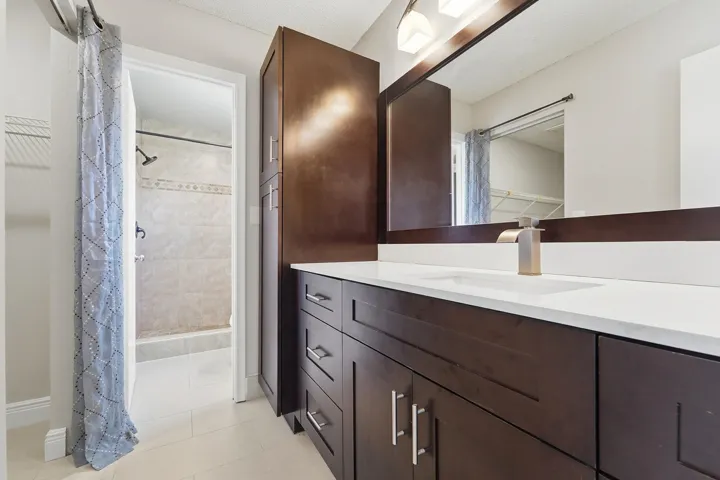 Dark wood-finish vanity with a white countertop and integrated sink