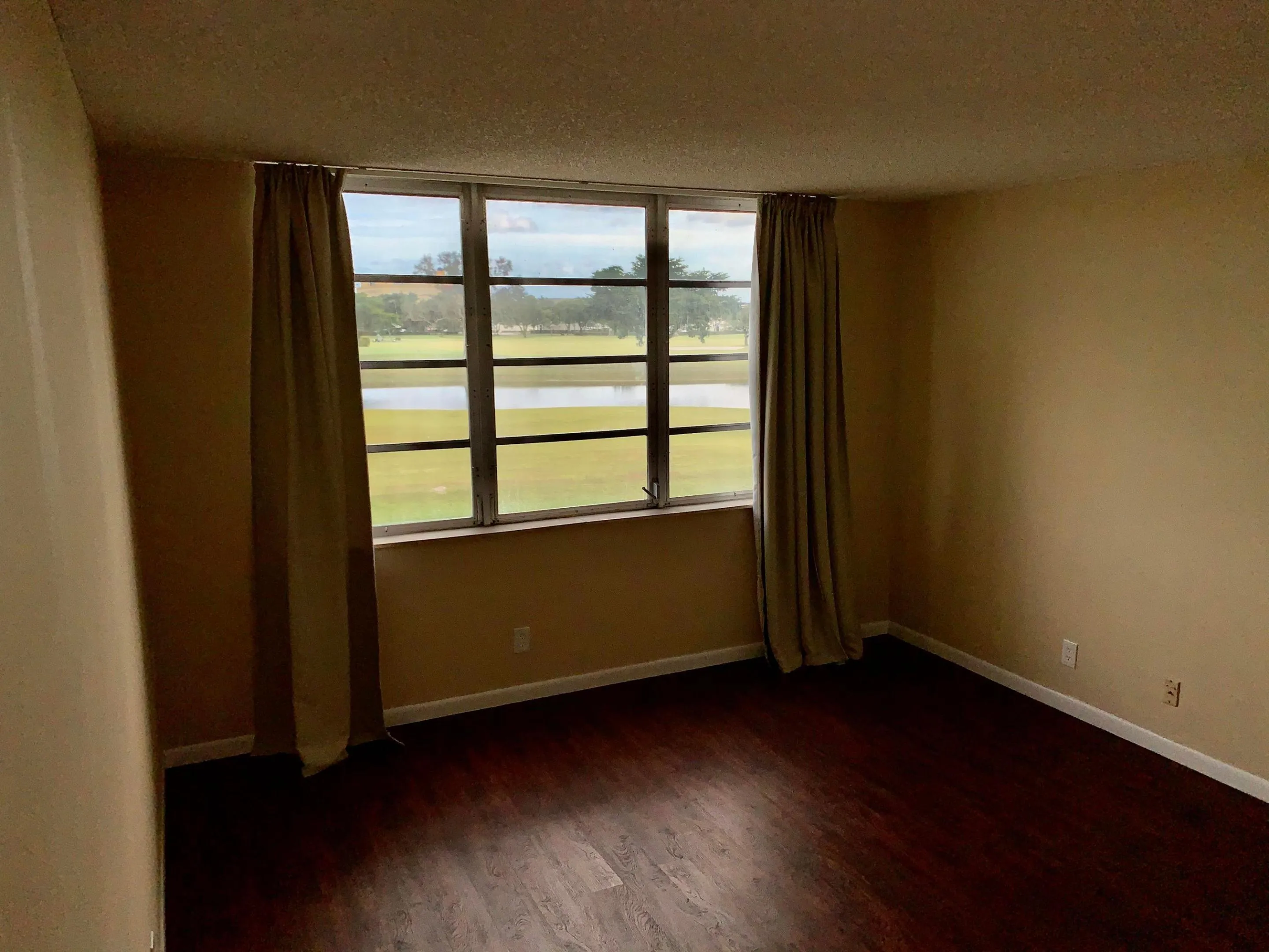 Room featuring wood-finish flooring, neutral wall tones, and a large window with a multi-pane design