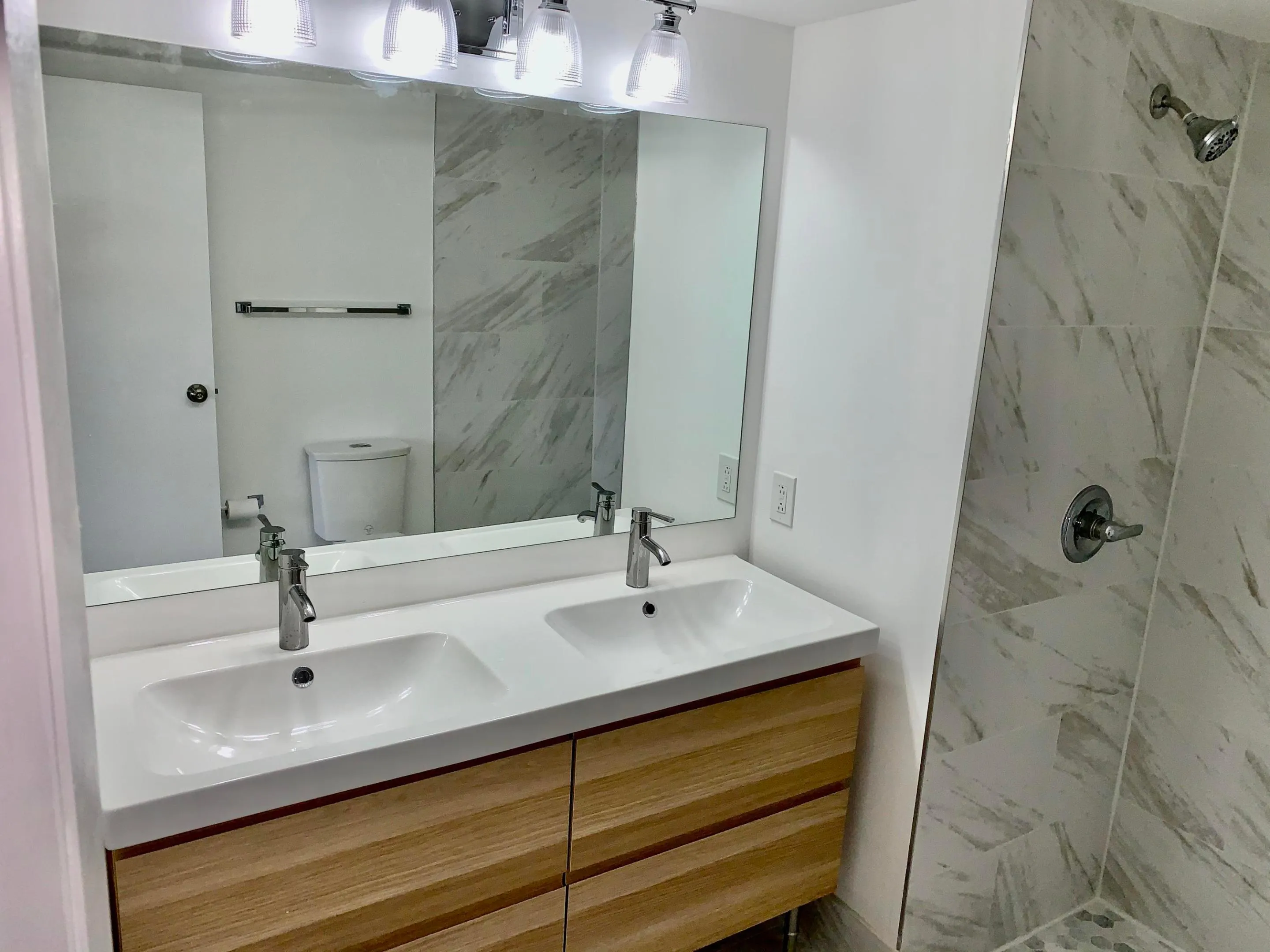 Double vanity featuring an integrated white sink, wood-finish cabinetry, and chrome fixtures