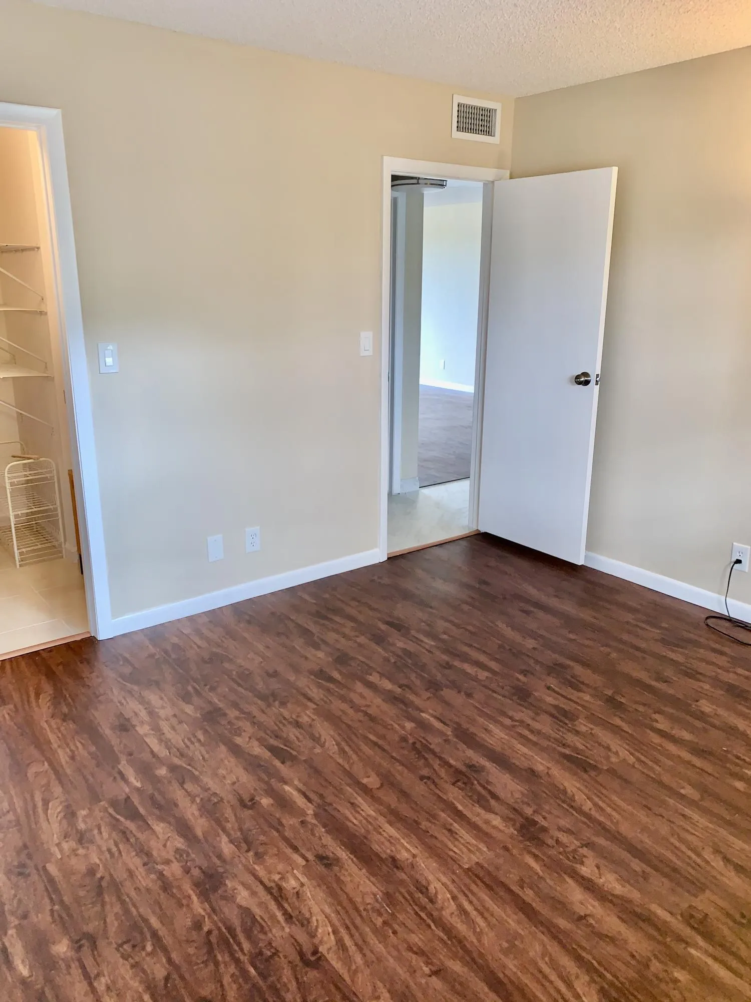 Wood-finish flooring throughout, featuring a neutral wall palette, white baseboards, and a built-in closet system