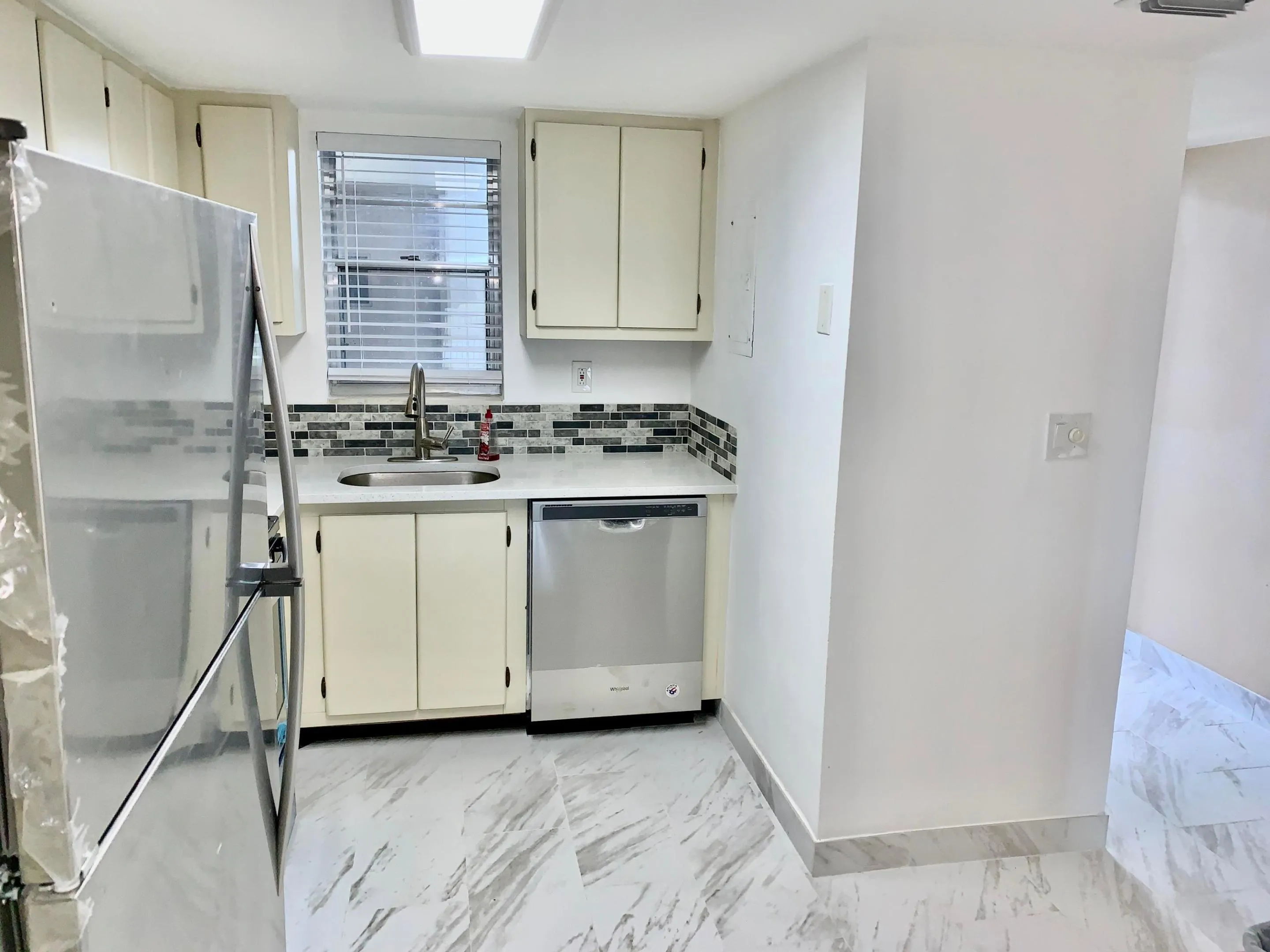 Kitchen featuring white cabinetry, a stainless steel refrigerator, and a coordinating stainless steel dishwasher