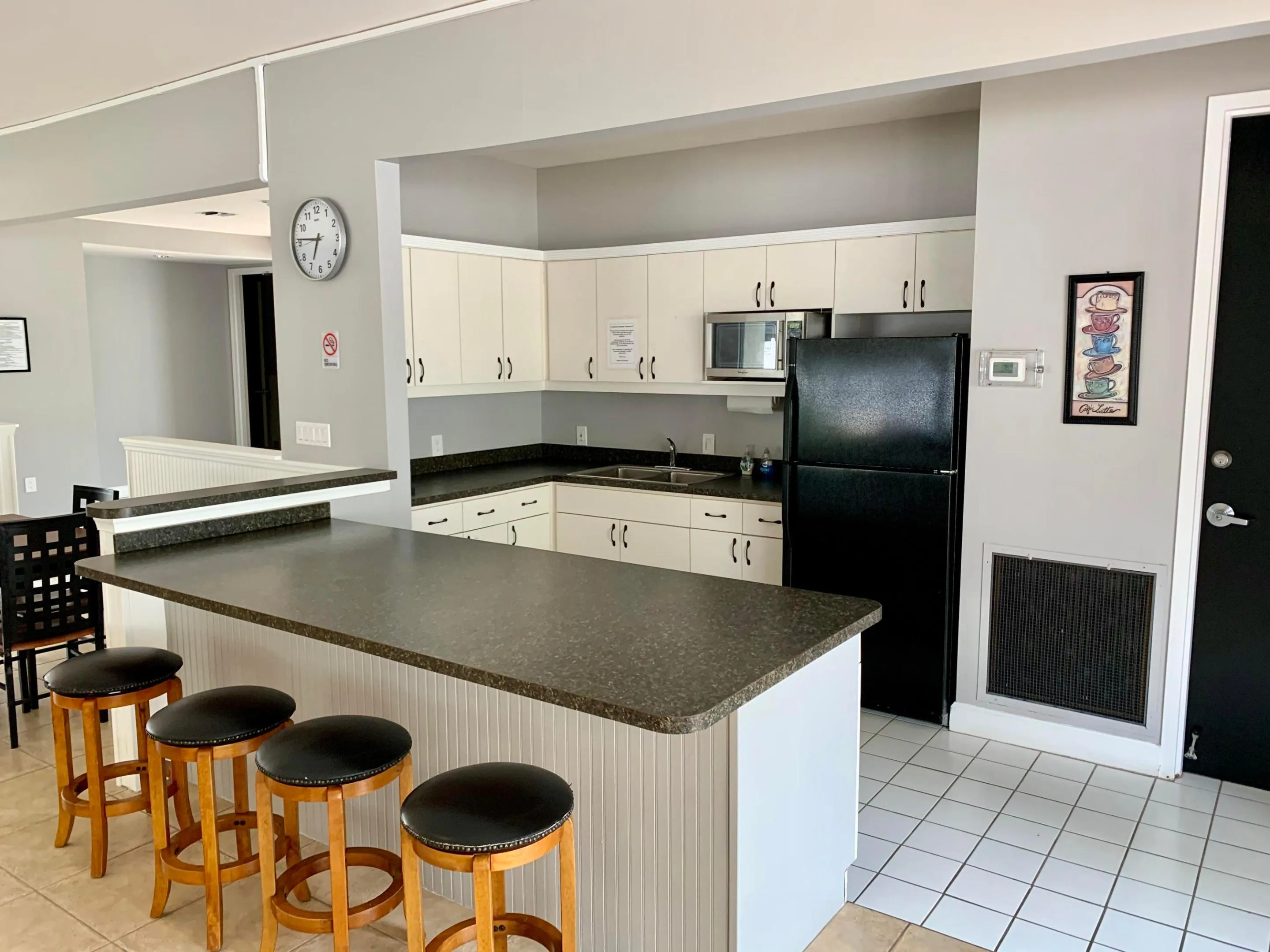 Kitchen area featuring white cabinetry, dark countertops, a black refrigerator, and a built-in microwave