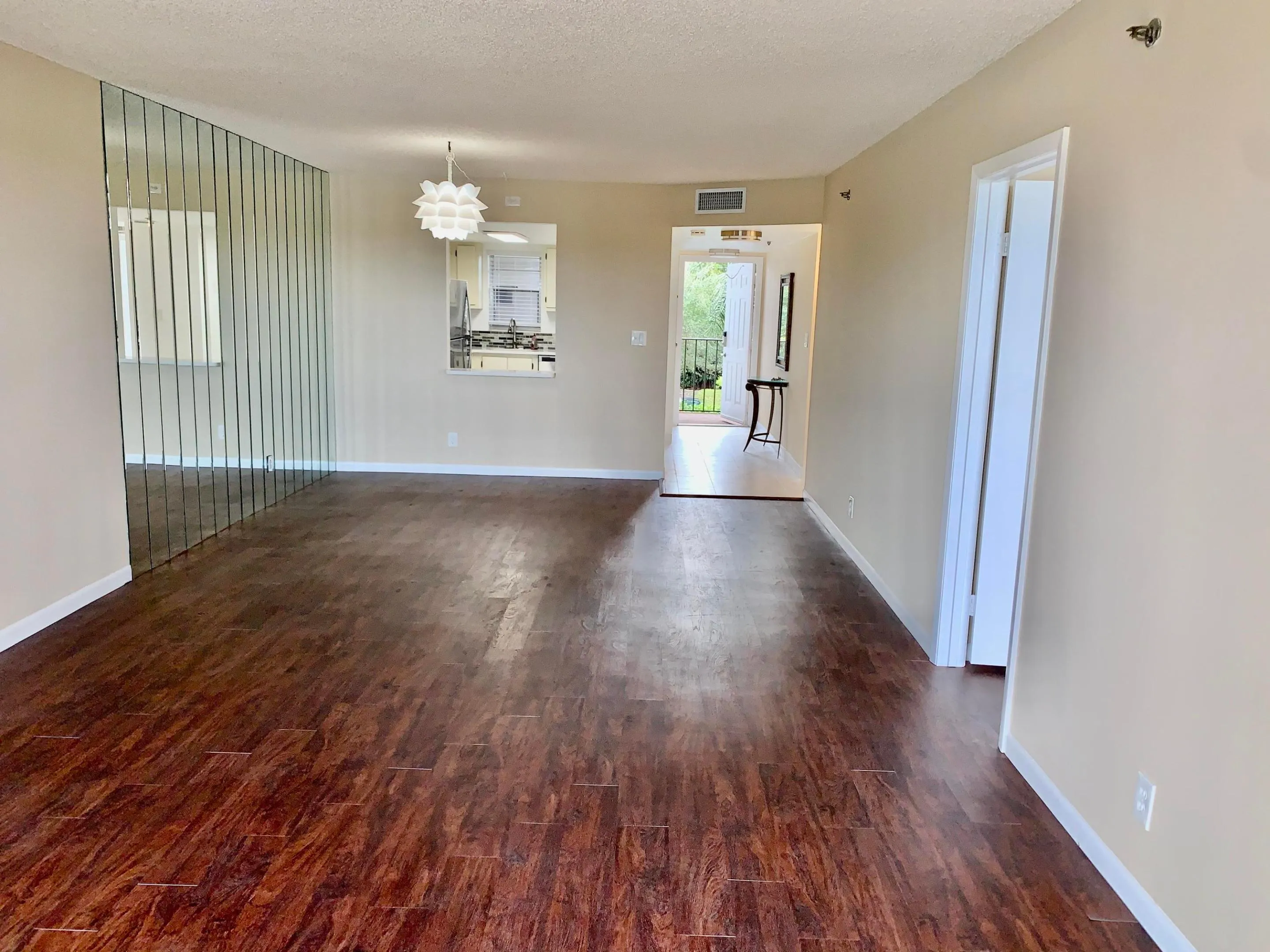 Spacious interior featuring wood-finish flooring, neutral-toned walls, and a decorative mirror wall accent