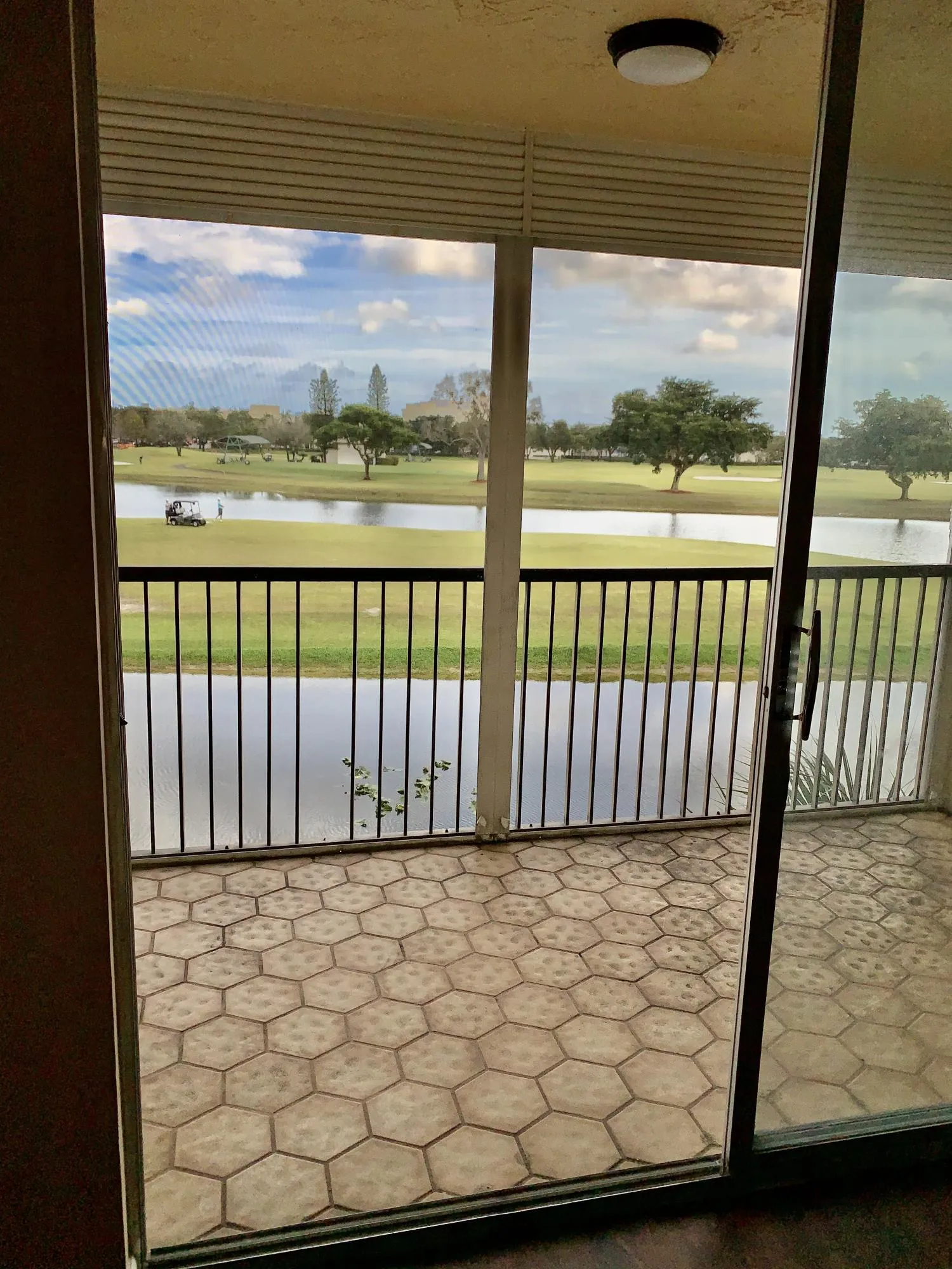 Patio featuring hexagonal tile flooring and a black metal railing overlooking a water feature and golf course