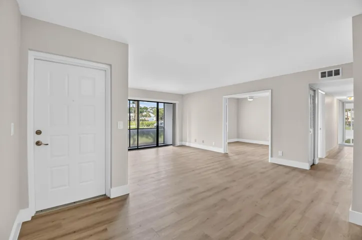 Entryway with wood-finish flooring, light neutral wall tones, and floor-to-ceiling sliding glass doors