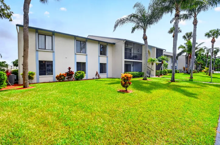Two-story exterior with light-colored stucco, blue trim accents, multiple windows, and screened balconies