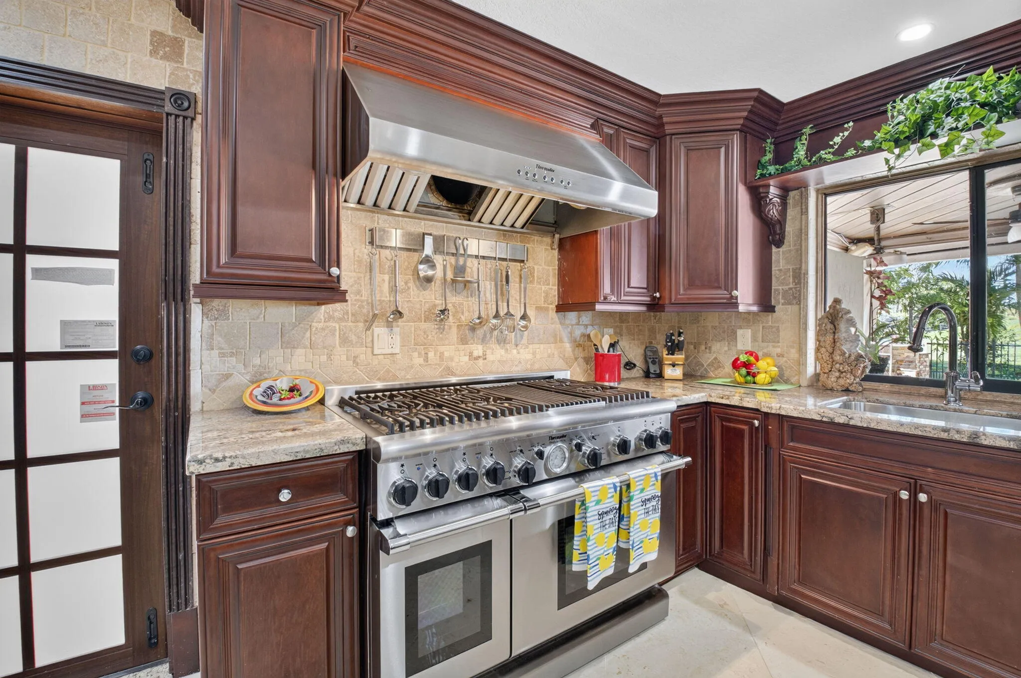 Professional Thermador GAS range with a grill and exhaust fan to the outside. Impact French door to the paver patio.