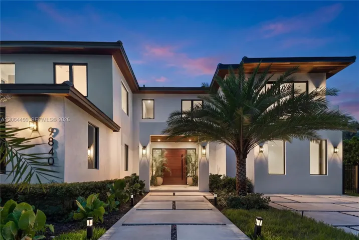Front elevation at dusk, warmly lit against the evening sky