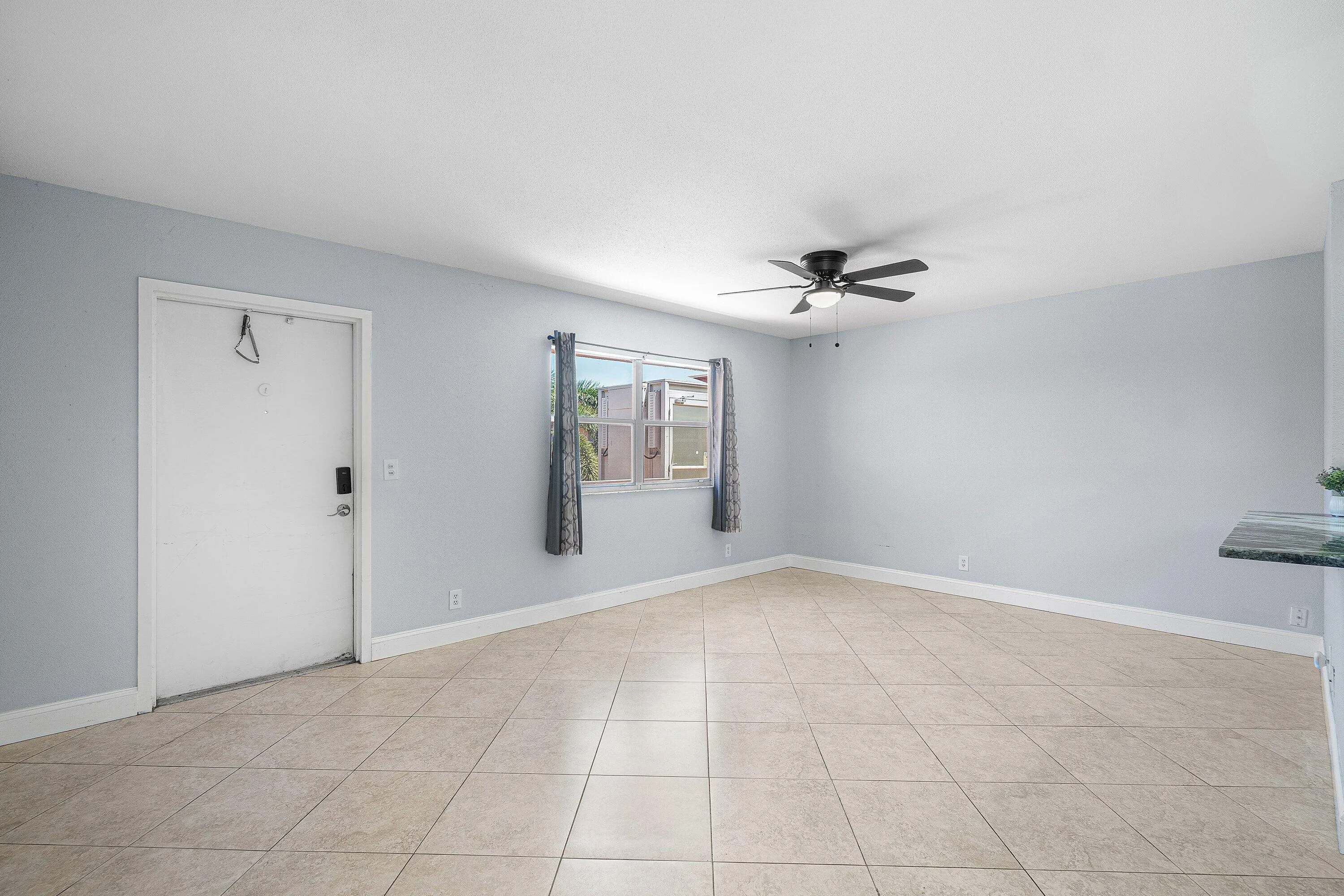 Light-toned tile flooring, ceiling fan with integrated lighting, and a window with natural light