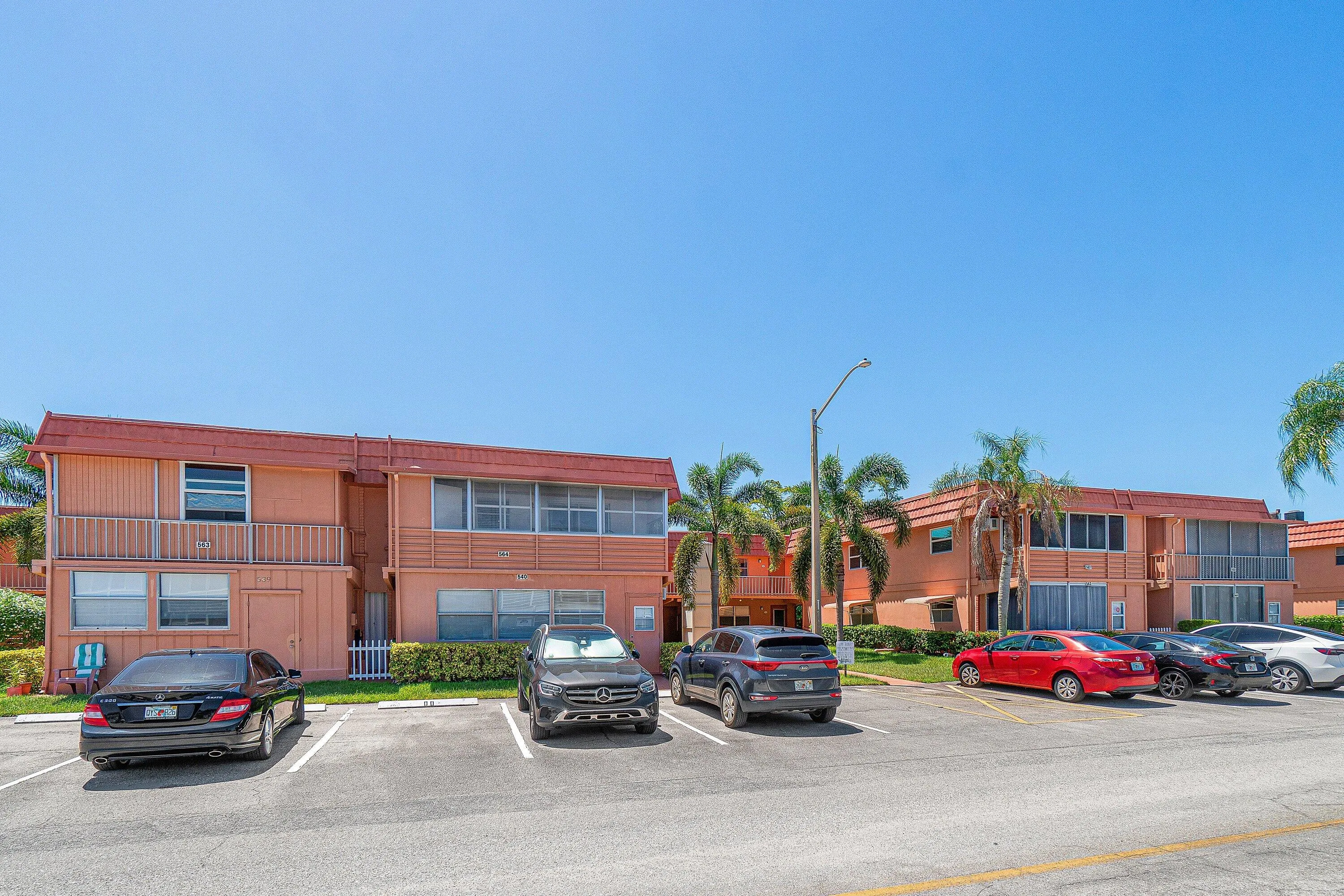 Multiple buildings featuring a stucco exterior, red tile roofs, and a paved parking area