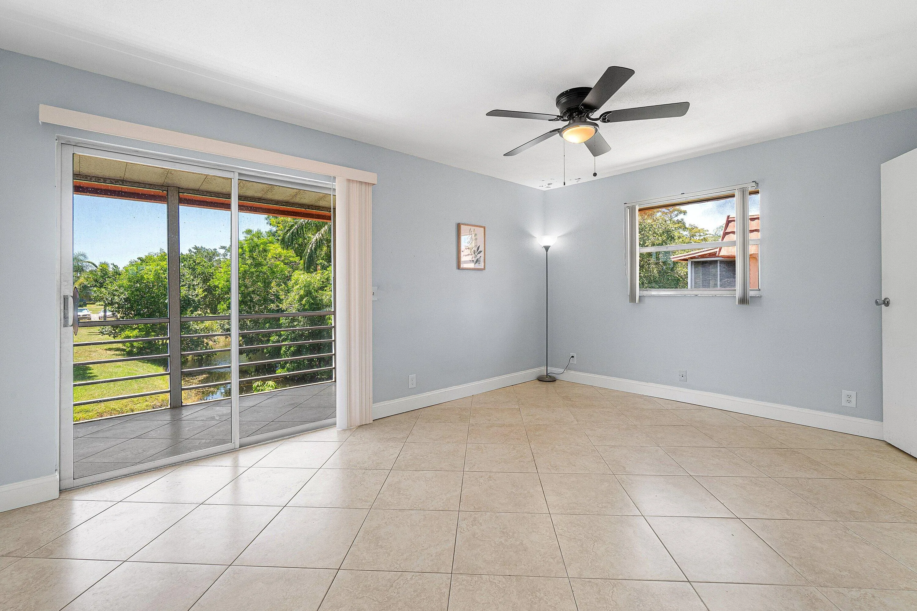 Light-colored tile flooring, ceiling fan with integrated lighting, sliding glass door leading to a balcony, and a single window