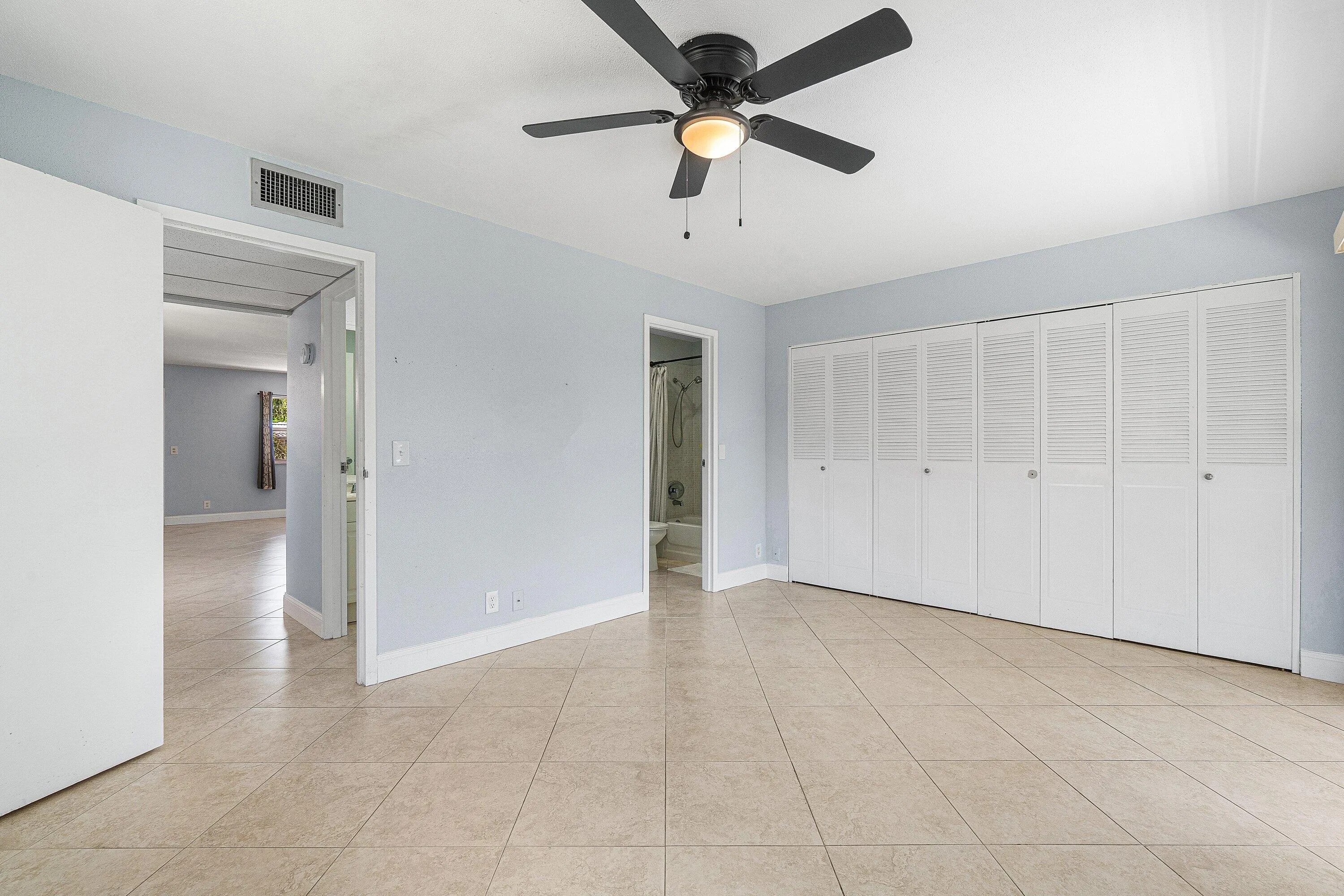 Light-toned tile flooring, white bi-fold louvered closet doors, and a ceiling fan with integrated​​‌​​​​‌​​‌‌​‌‌​​​‌‌​‌​‌​‌​​​‌​​ lighting