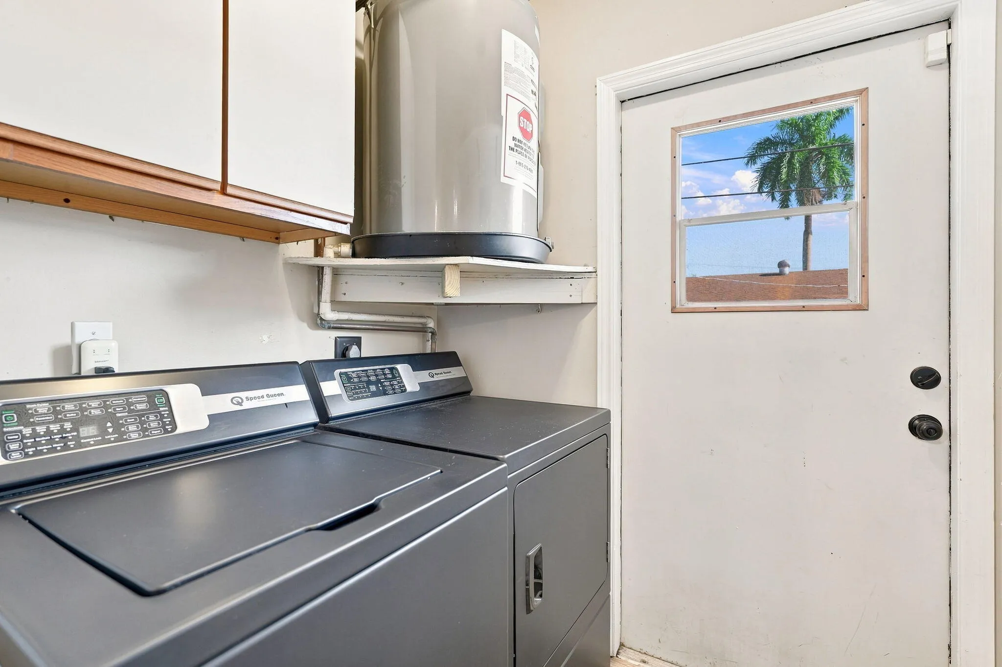 White wall cabinets with wood trim, water heater and an exterior door with a window insert