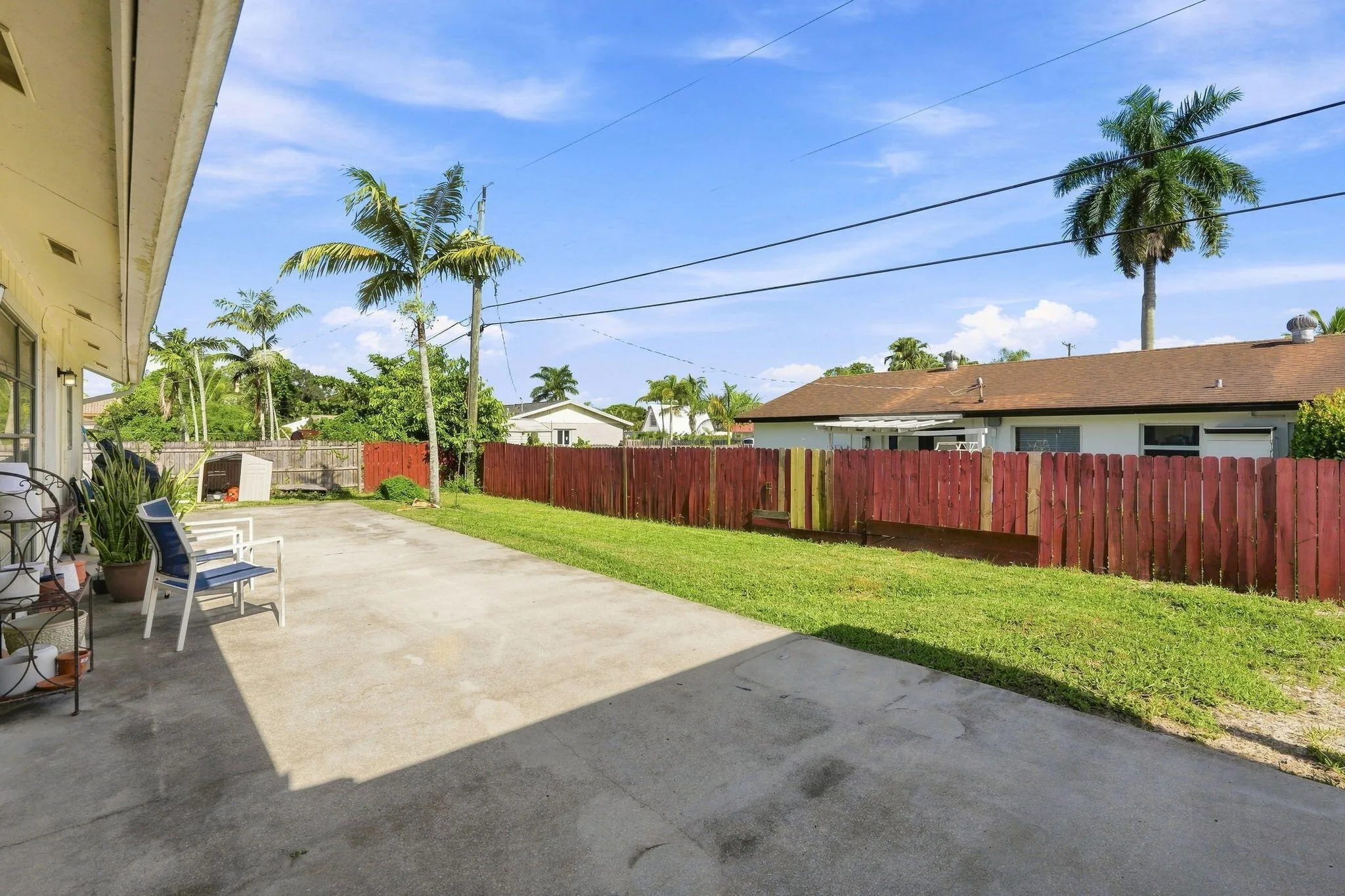 Expansive concrete patio with a red wood fence and green lawn